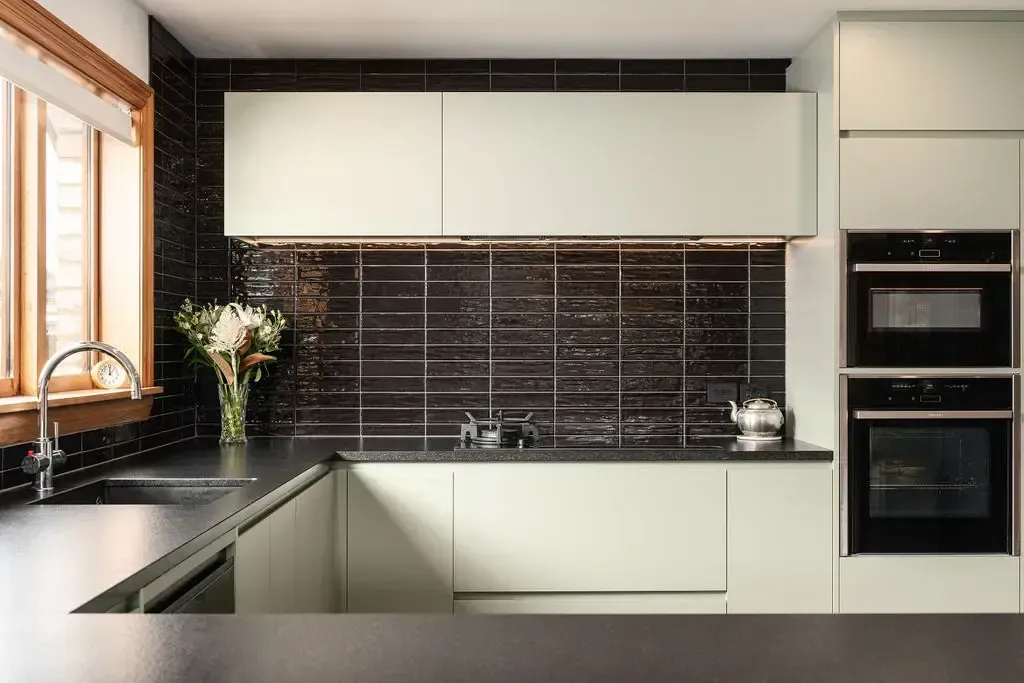 A kitchen with white cabinets and black counter tops