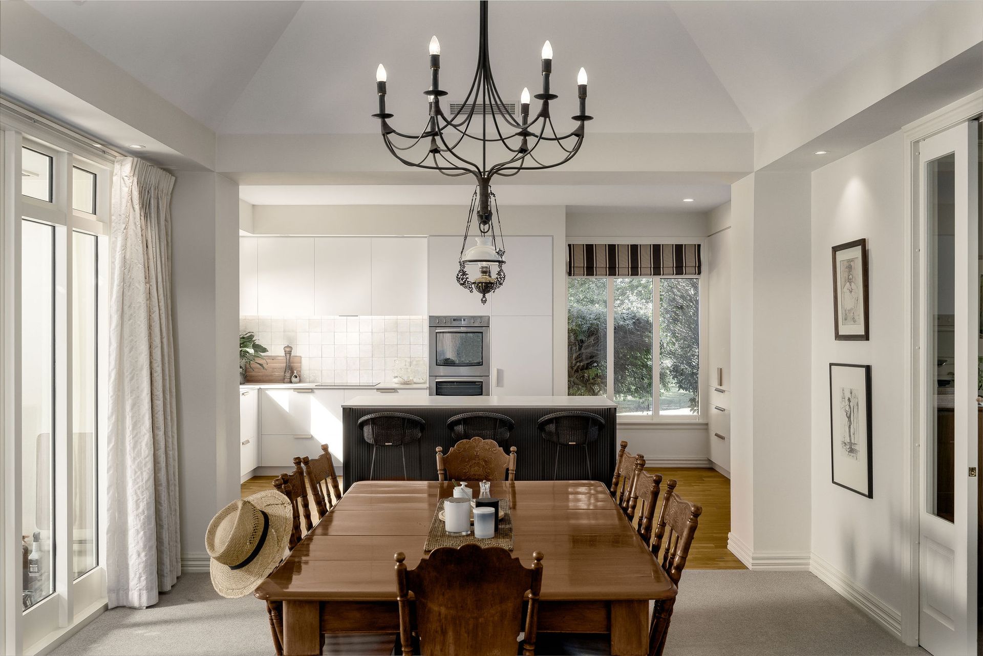 A dining room with a wooden table and chairs and a chandelier hanging from the ceiling.