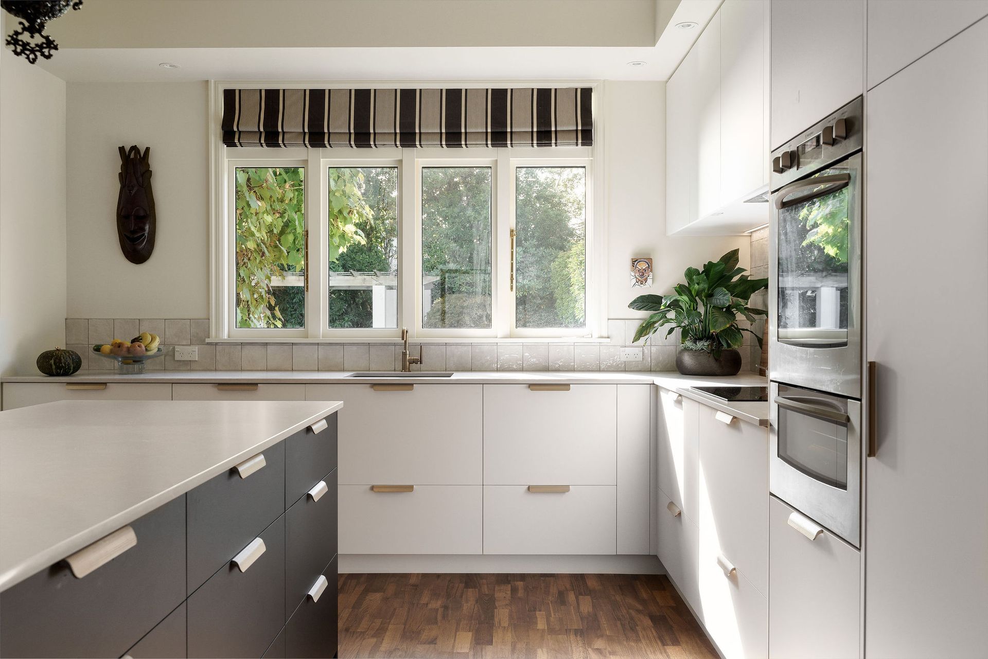 A kitchen with white cabinets and black drawers and a stainless steel oven.