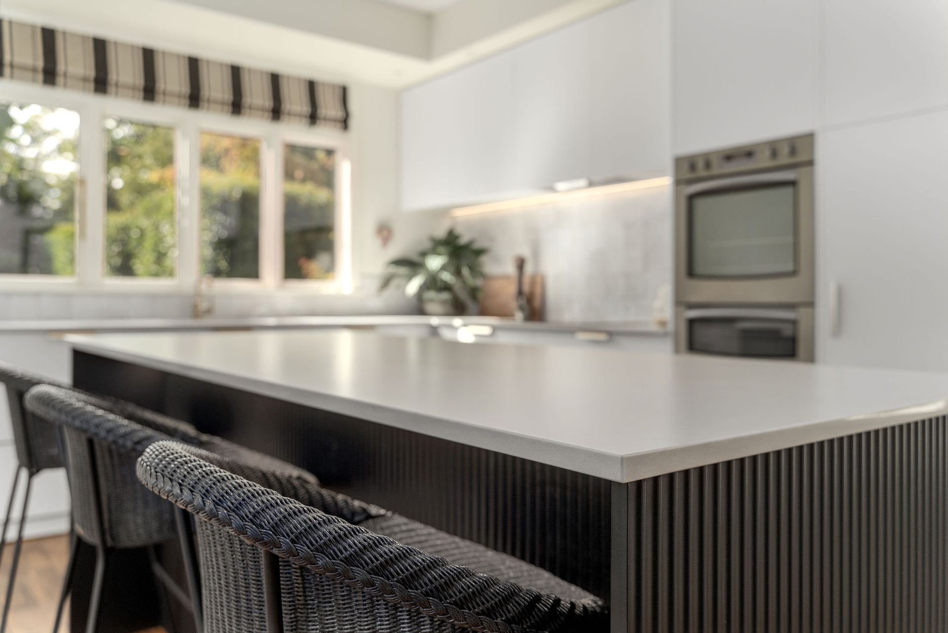 A kitchen with a large island , stools and a stove.