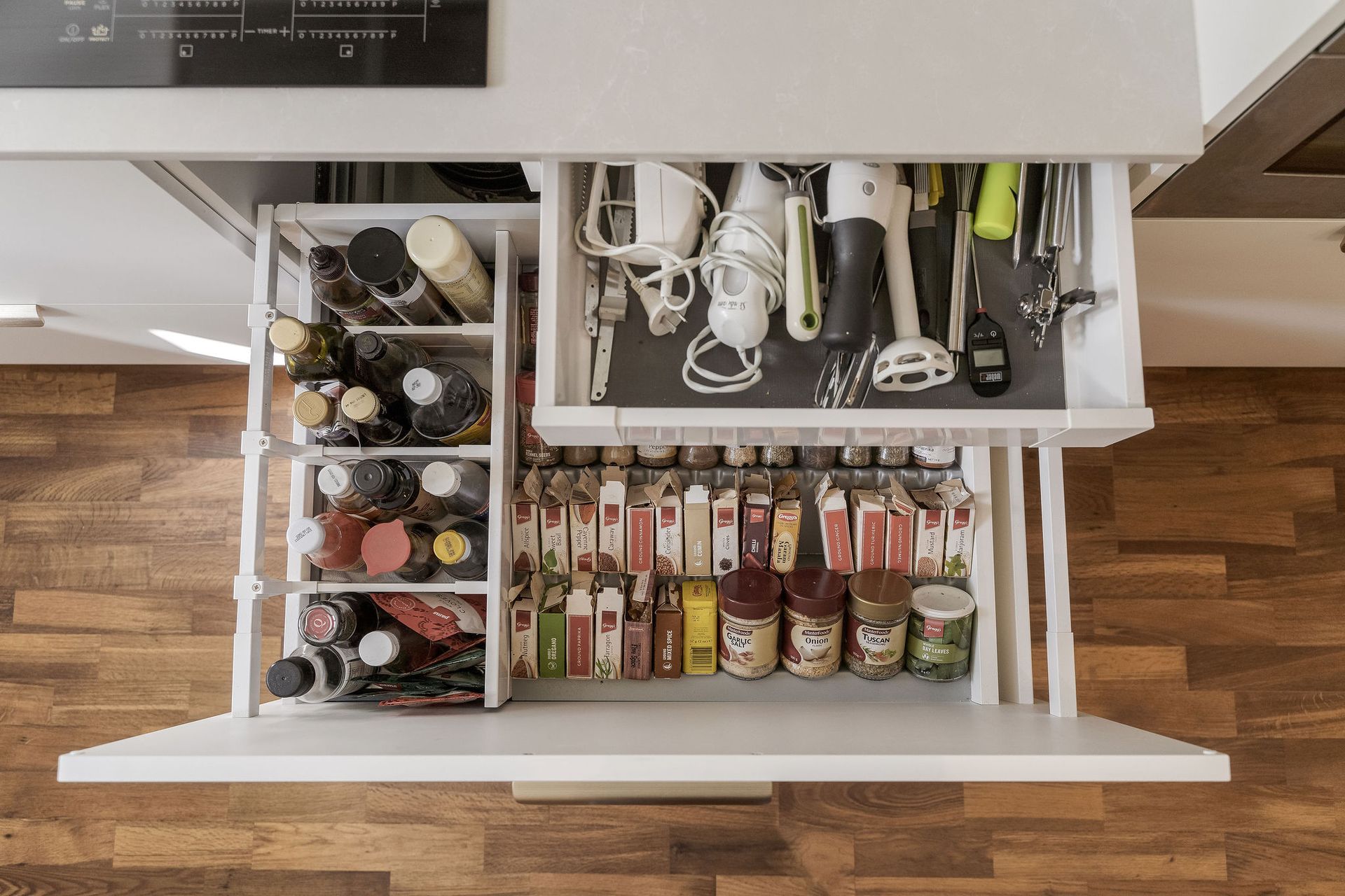 A kitchen drawer filled with bottles , jars , and utensils.