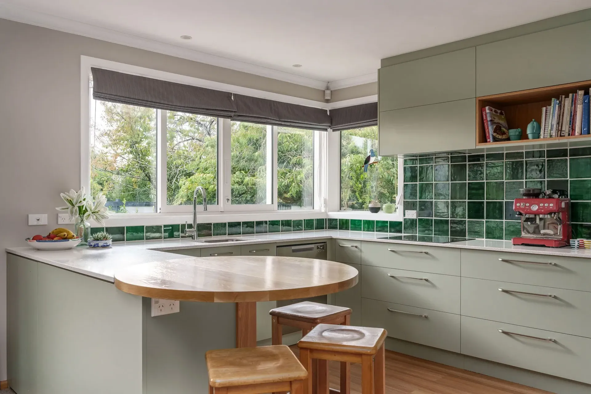 A kitchen with green tiles and a table and stools