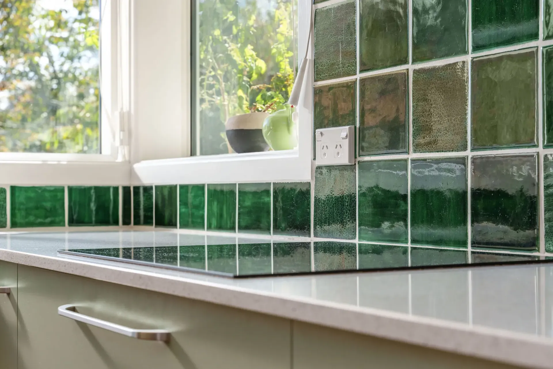 A kitchen with green tiles and a stove top oven.
