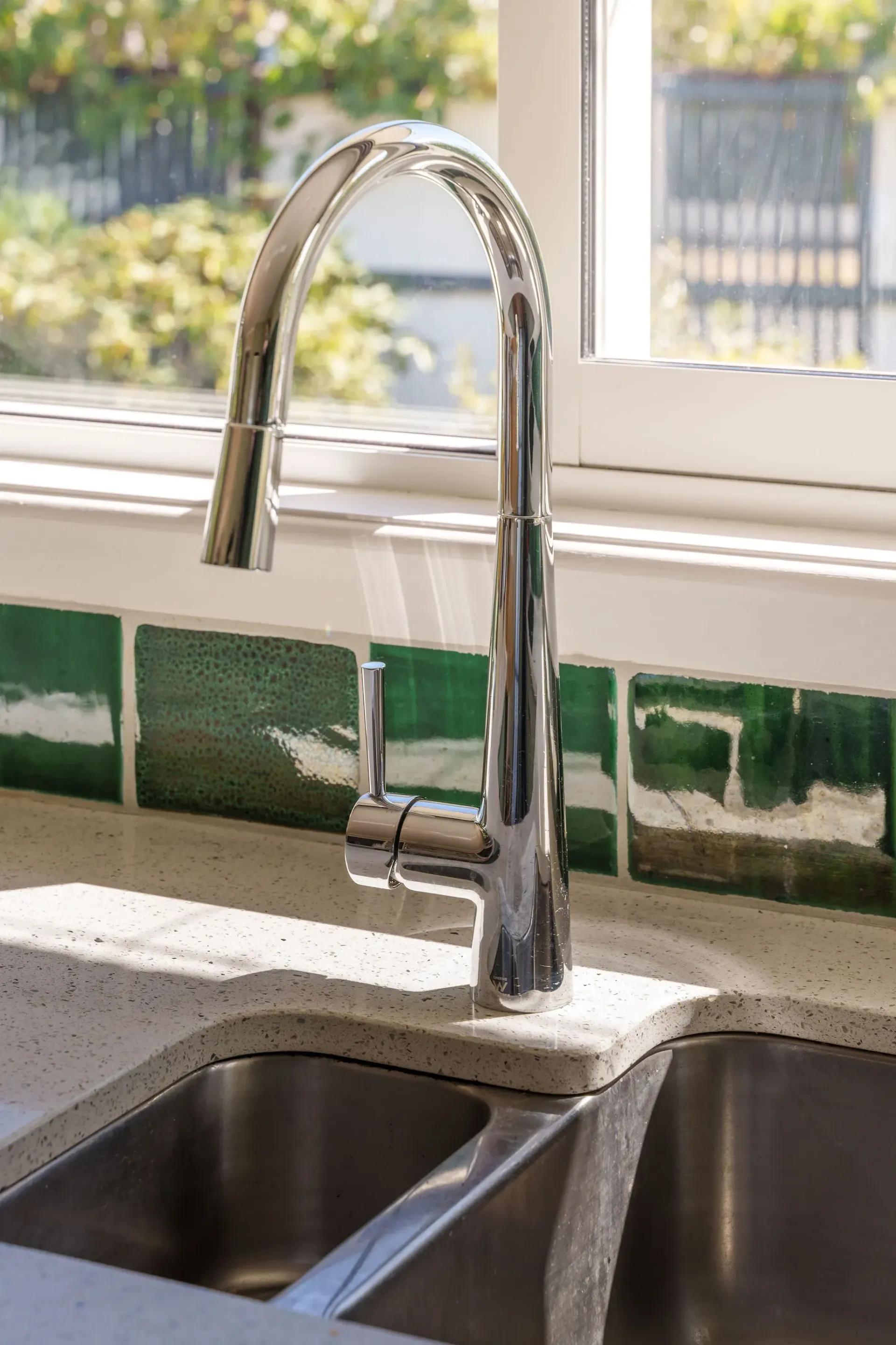 A kitchen sink with a faucet and a window in the background.