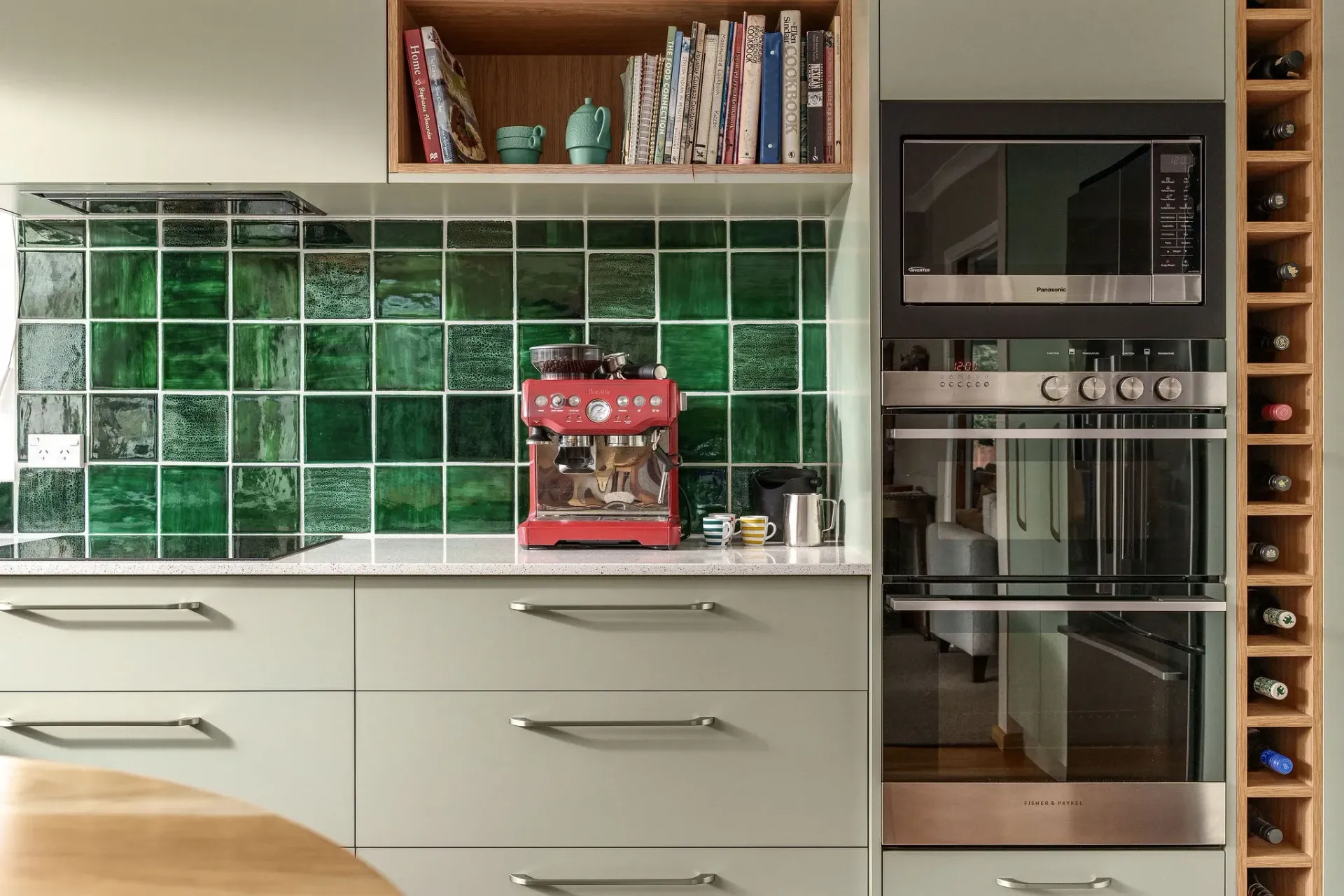 A kitchen with green tiles and a red coffee maker