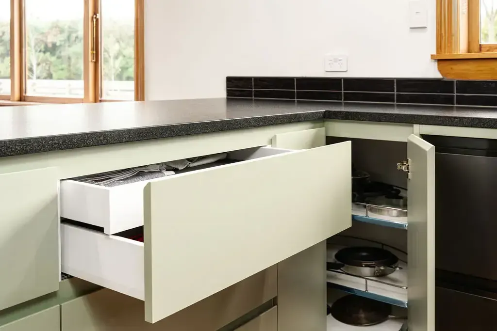 A kitchen with a drawer open filled with pots and pans