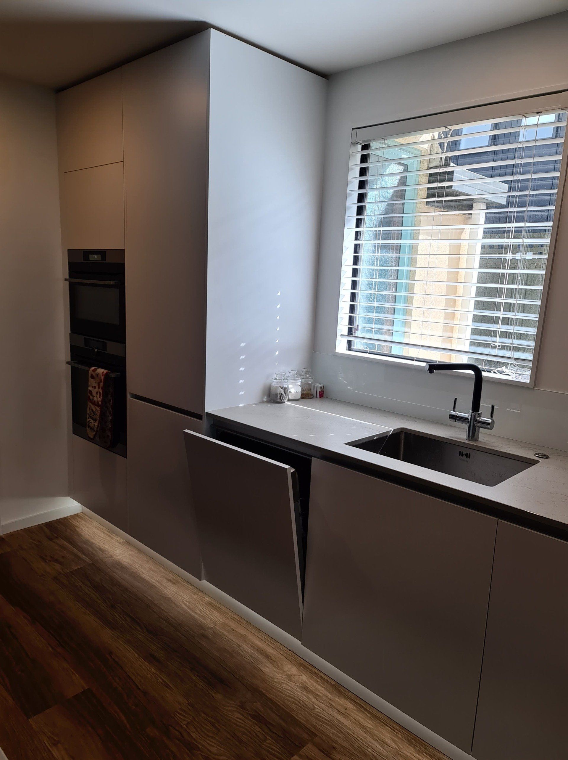 A kitchen with a sink and a window with blinds.