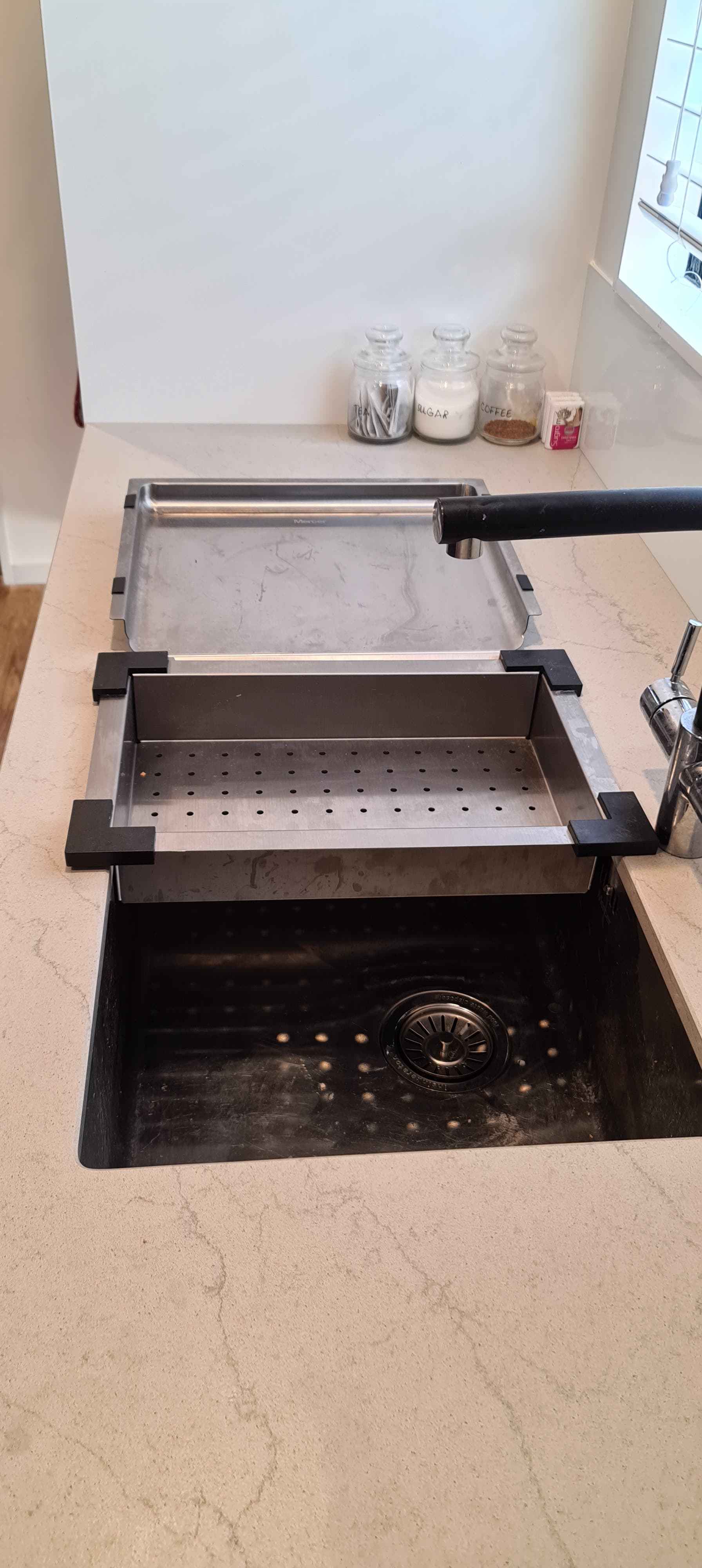 A kitchen sink with a strainer on top of it.