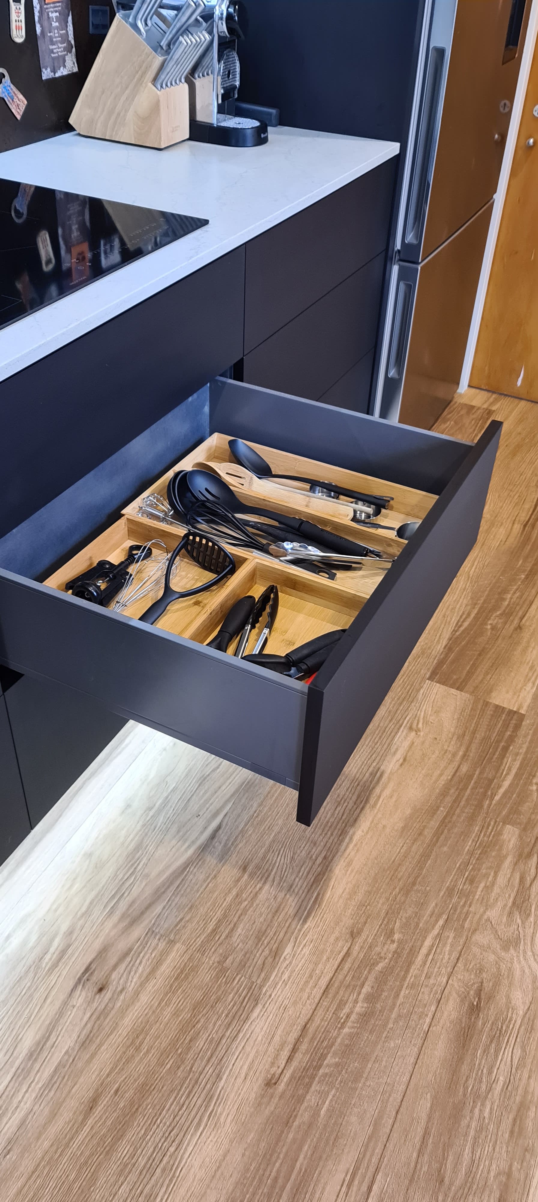 A kitchen drawer filled with utensils and a stove top oven.