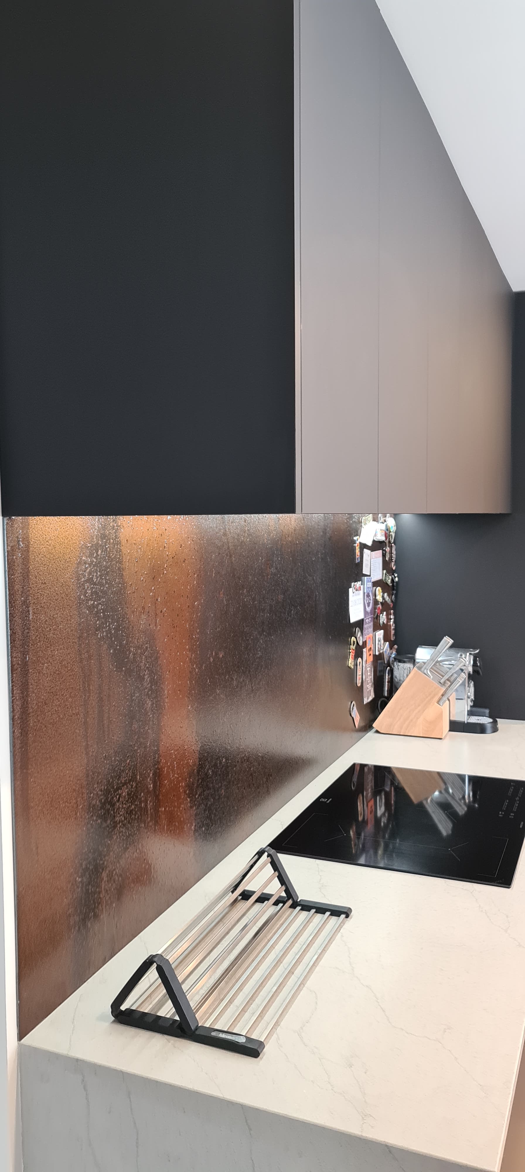 A kitchen with a stove top oven , sink , and black cabinets.