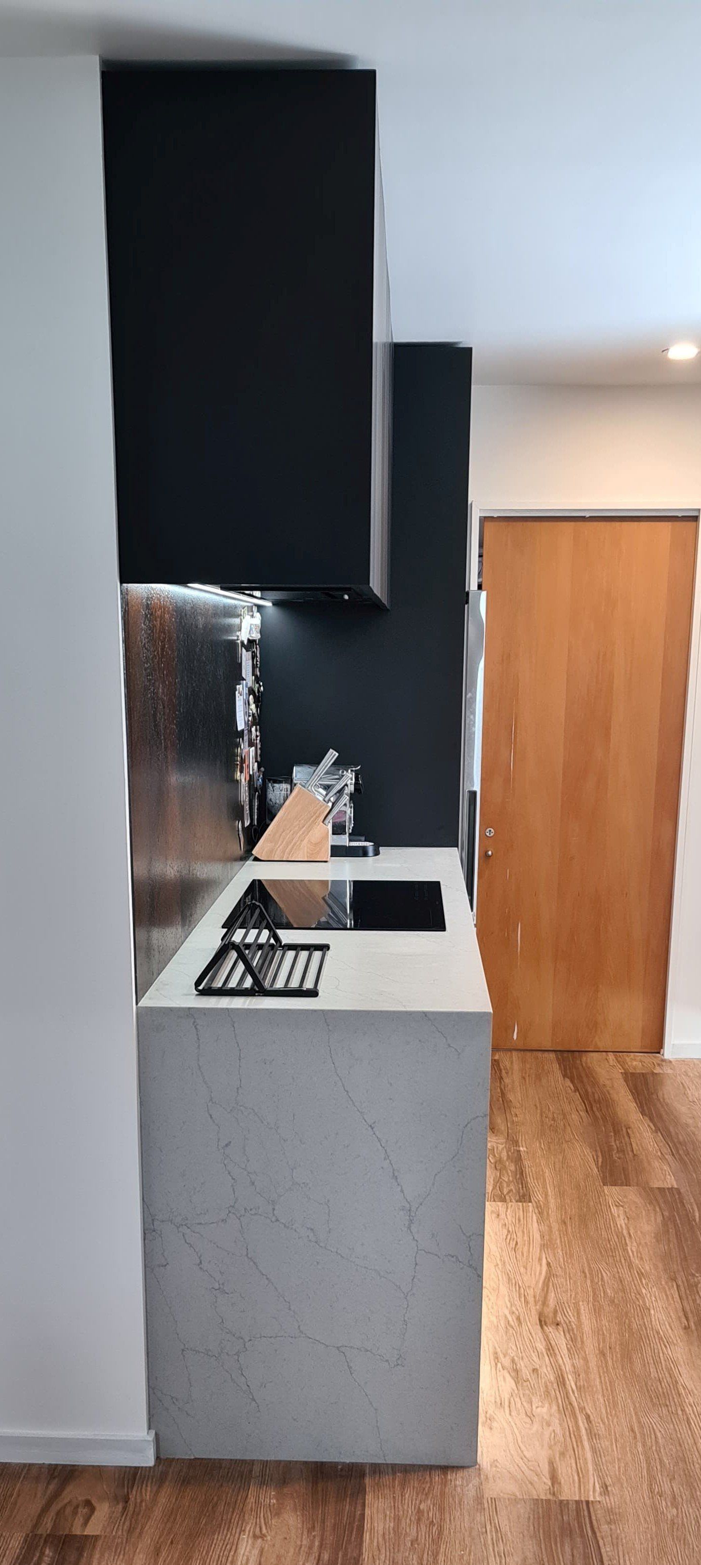 A kitchen with a stove top oven , sink , and black cabinets.