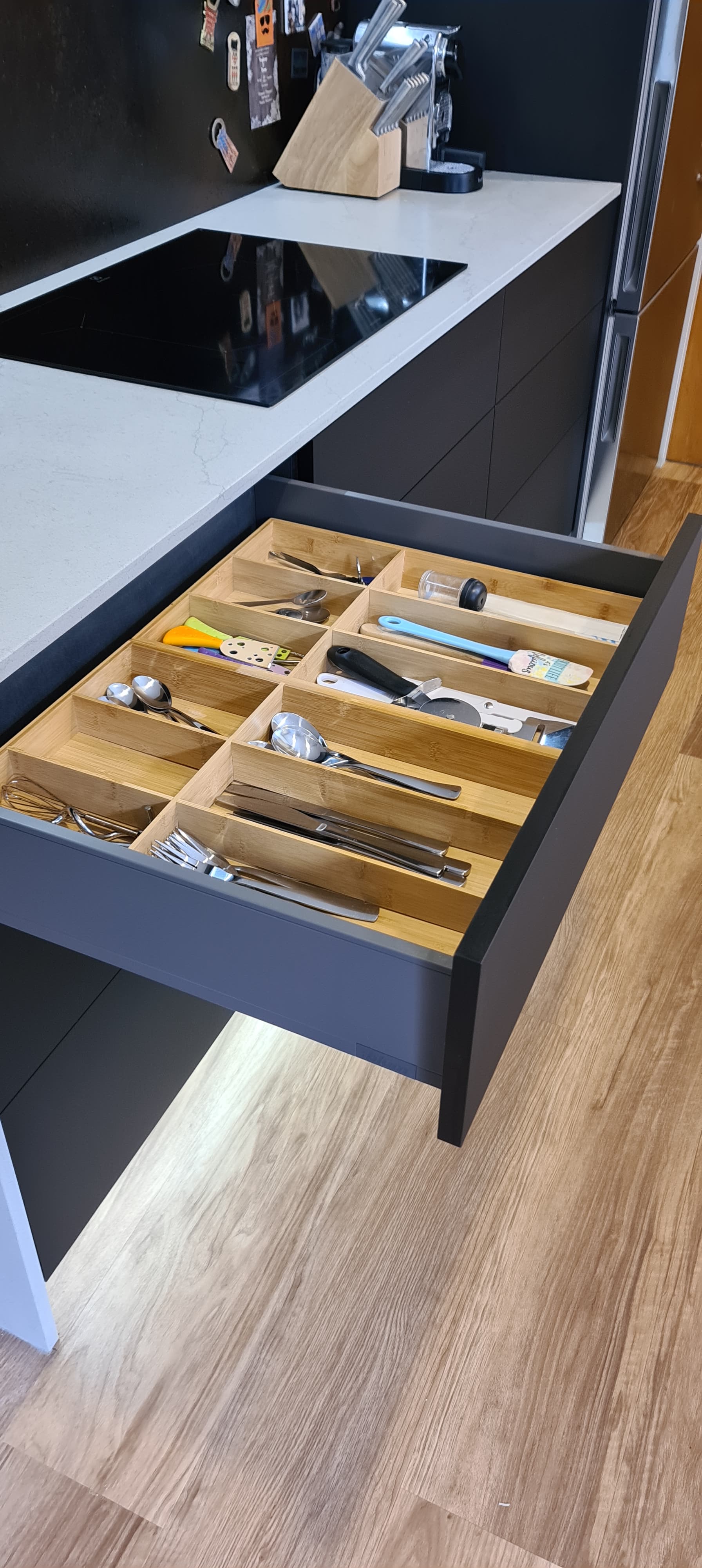 A kitchen drawer filled with utensils and a stove top oven.
