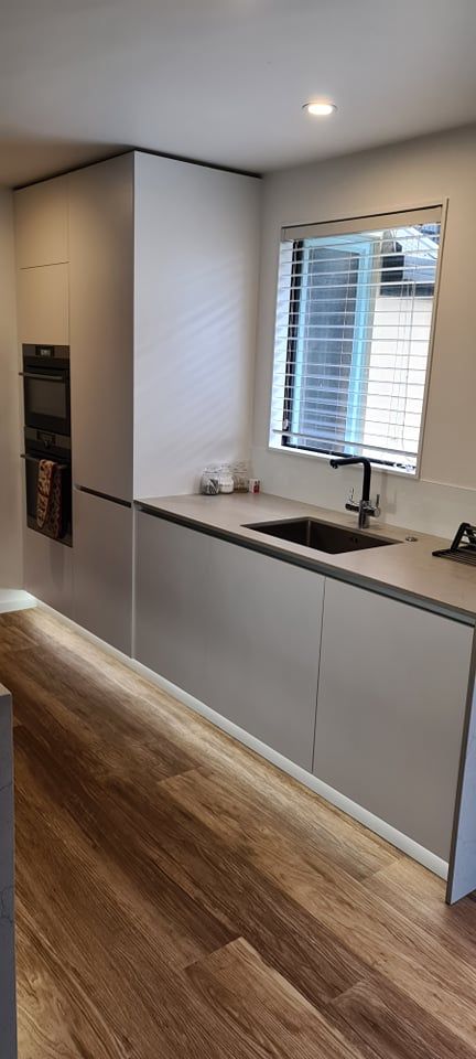 A kitchen with white cabinets , a sink , and a window.