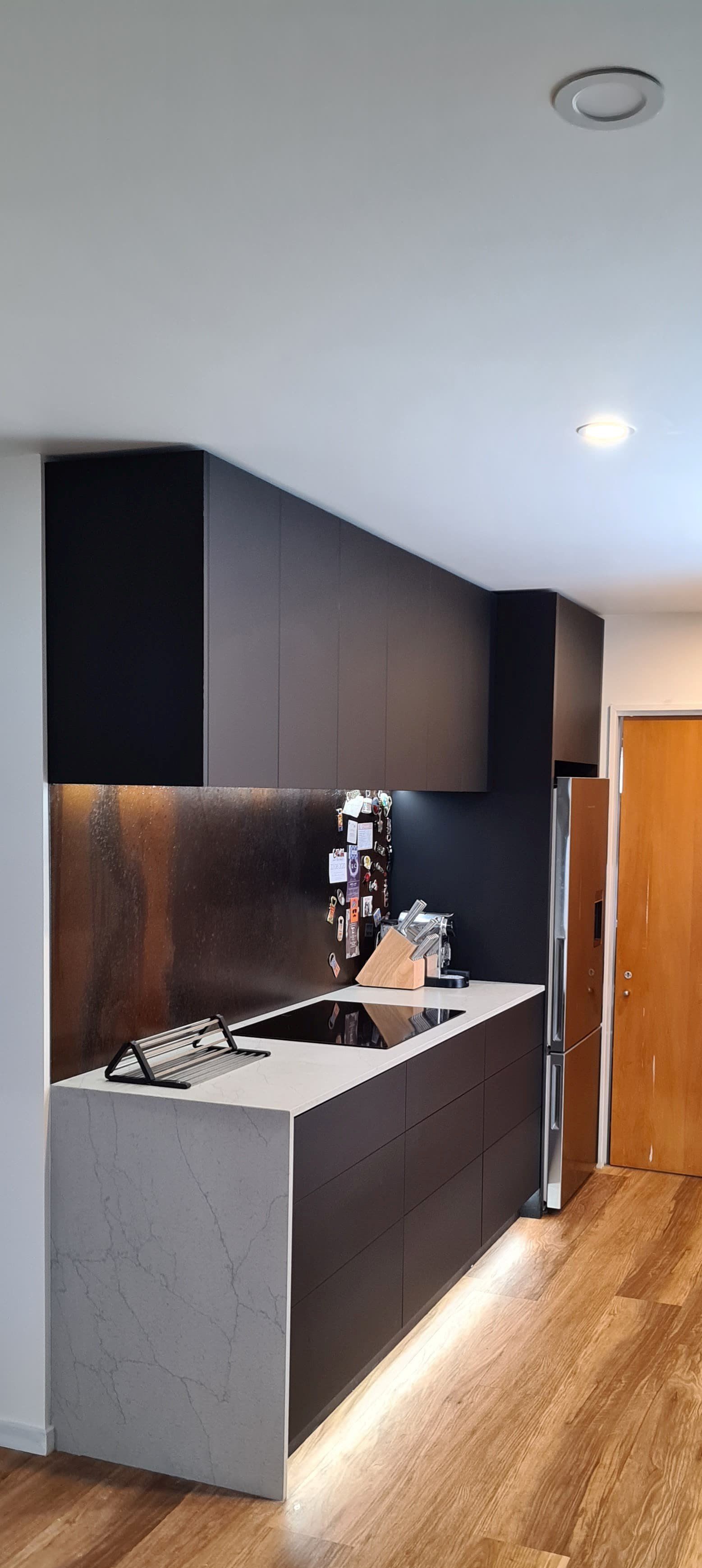 A kitchen with a sink , stove , refrigerator and cabinets.