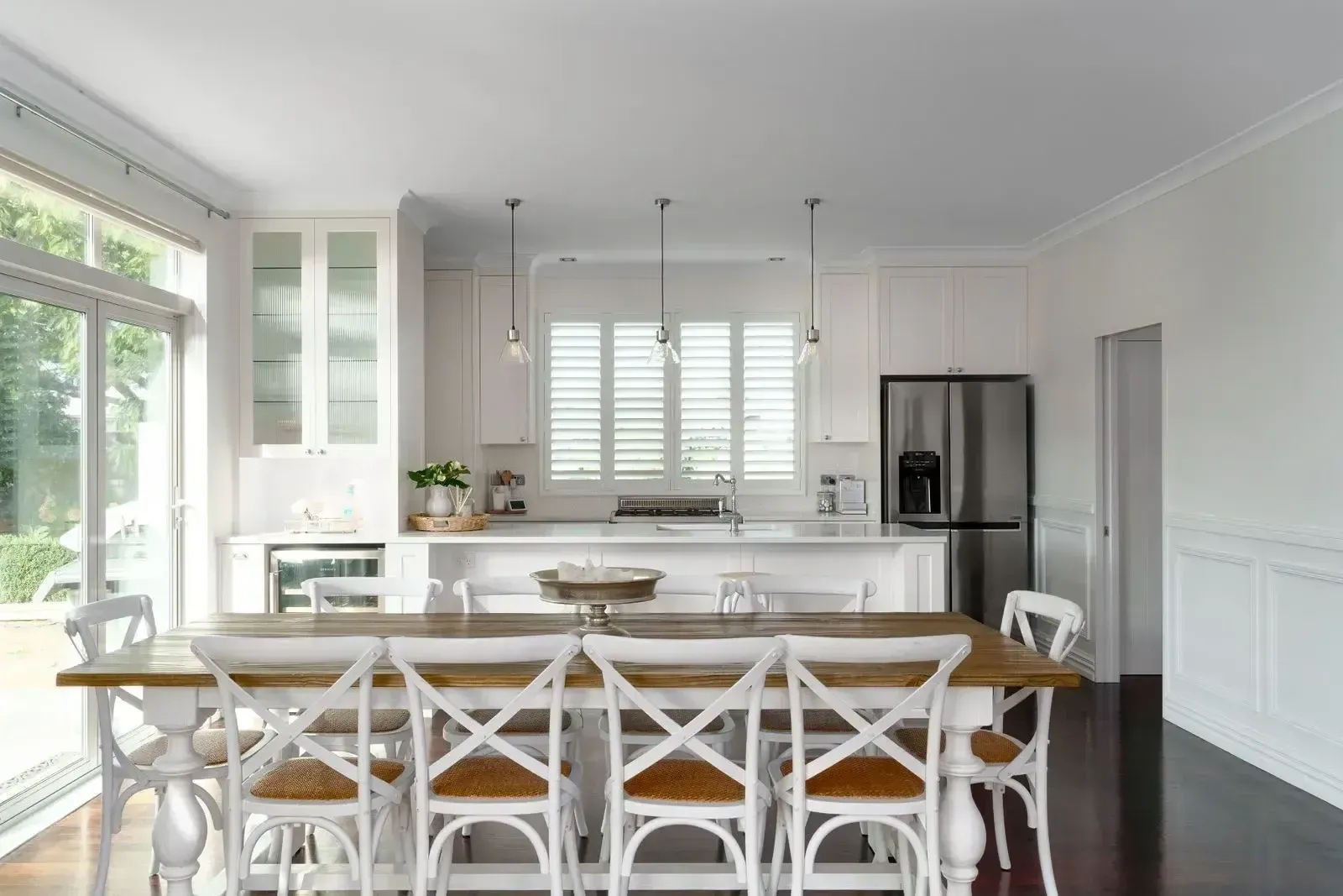 A kitchen with a dining table and chairs and a refrigerator.
