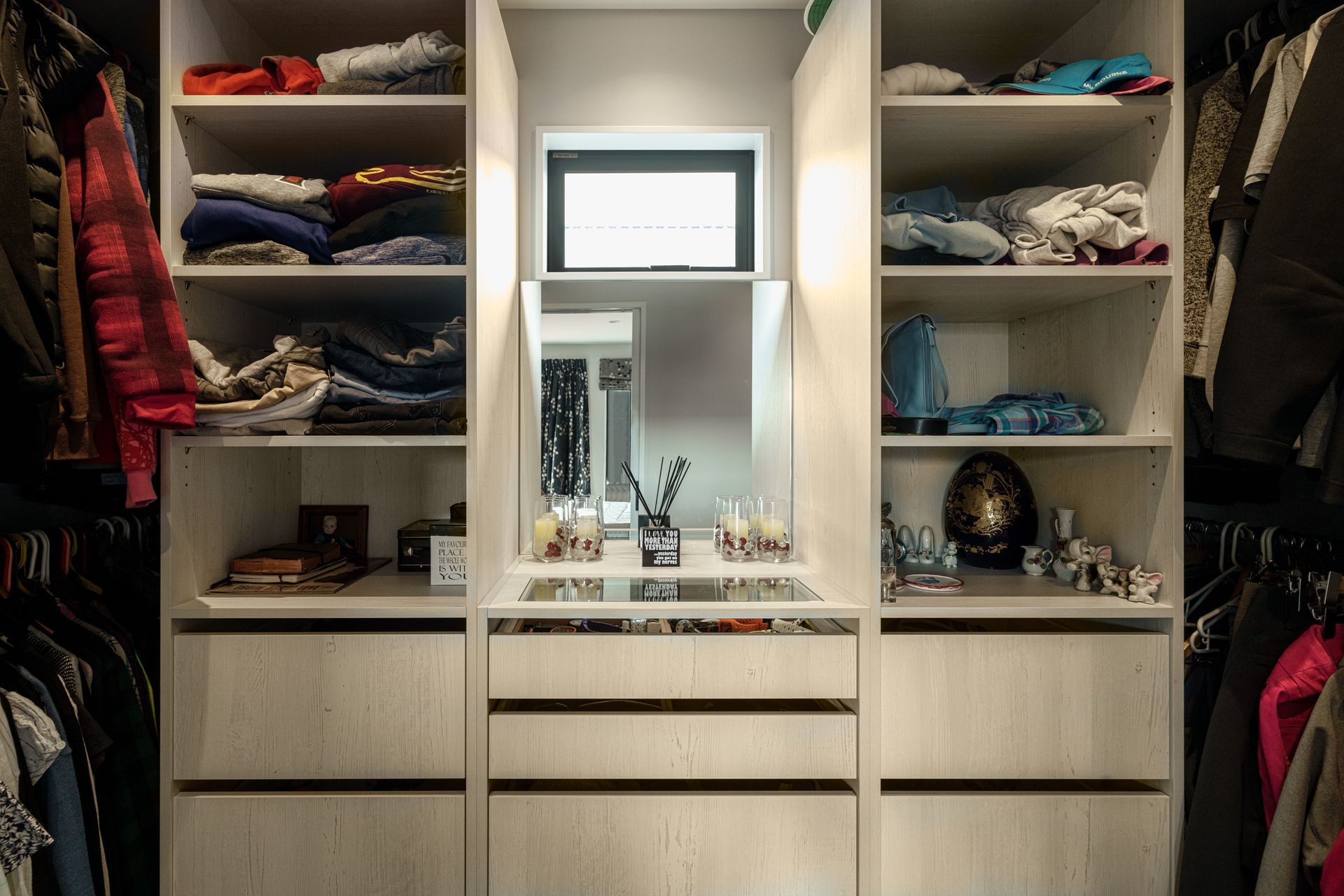 A walk in closet with lots of clothes and a mirror.