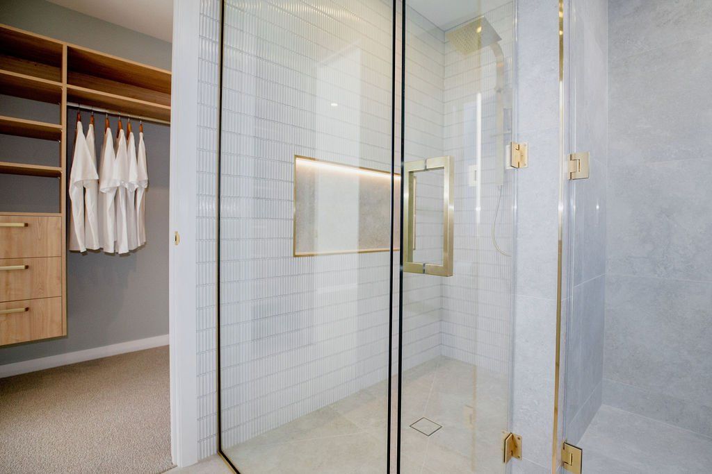 A bathroom with a walk in closet and a shower with a glass door.