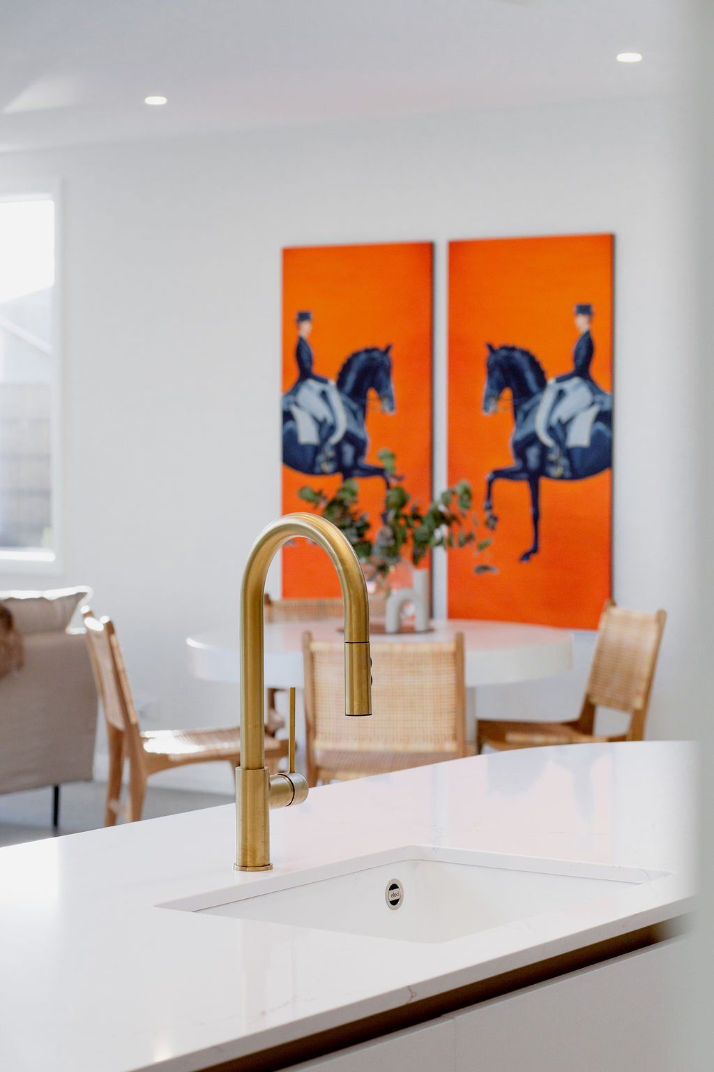 A kitchen with a sink and two paintings on the wall