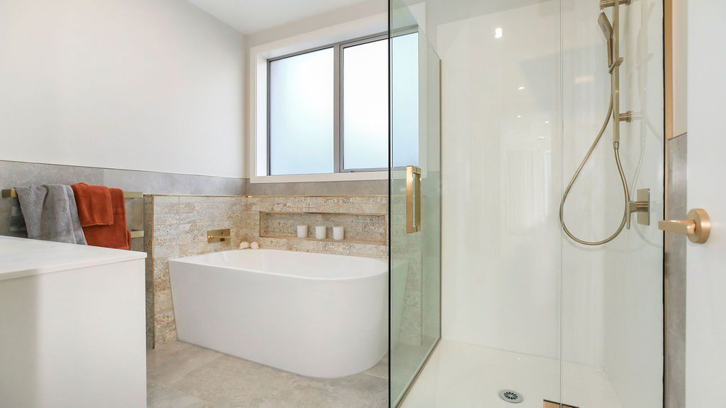 A bathroom with a bathtub , shower and window.