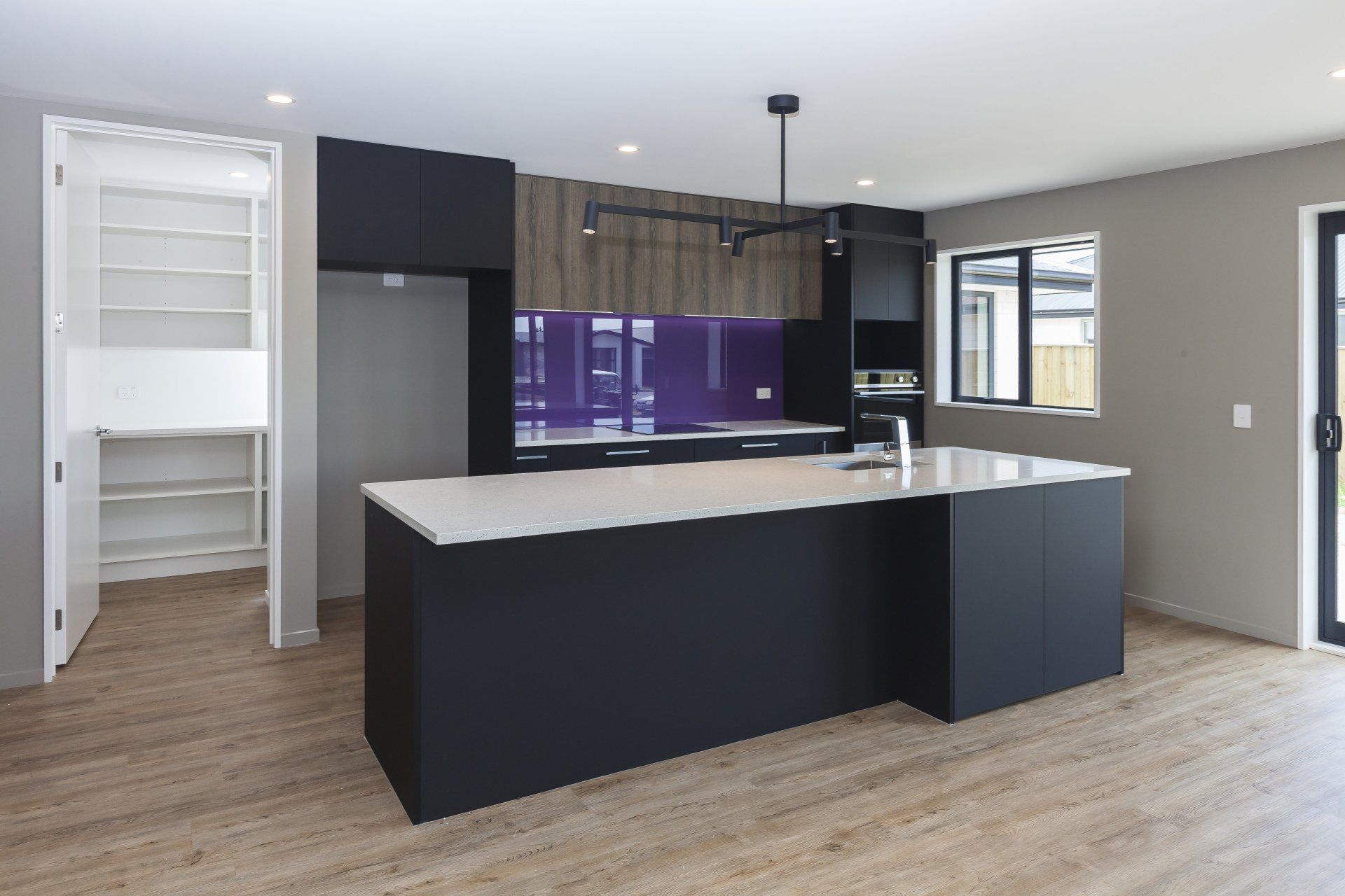 An empty kitchen with black cabinets and a large island.