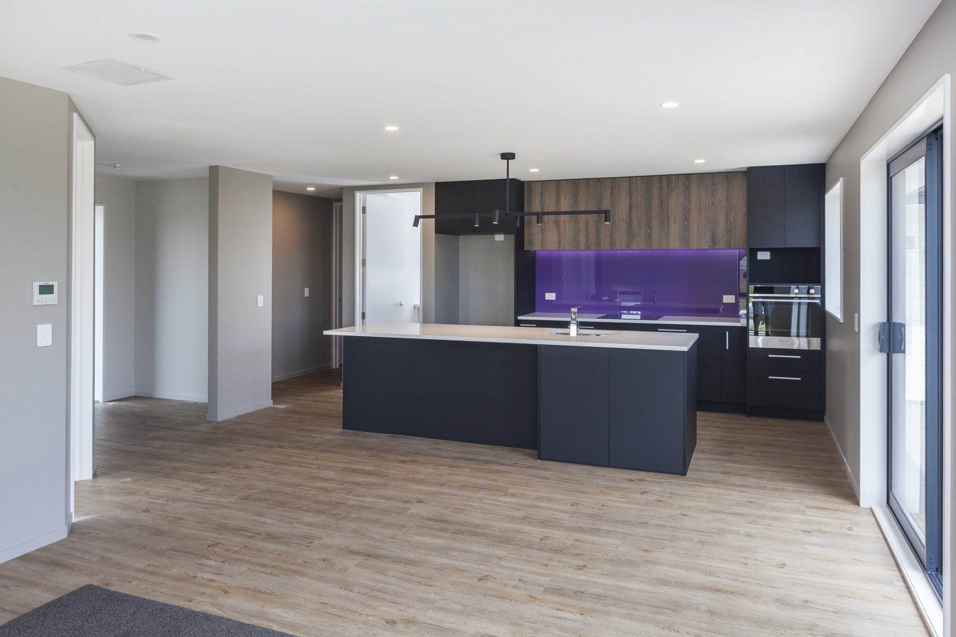 A kitchen with black cabinets and a purple backsplash