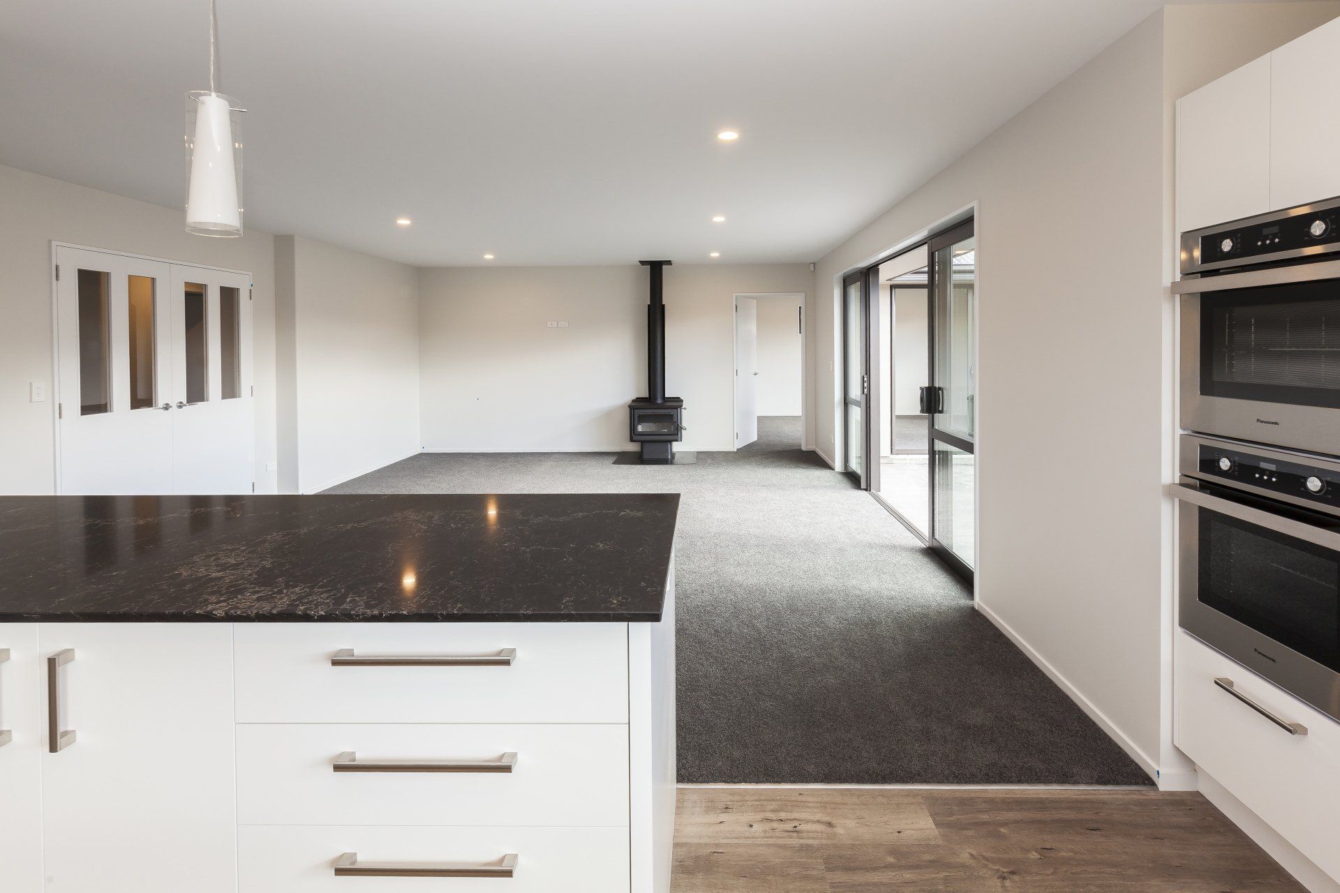 An empty kitchen with a black counter top and white cabinets