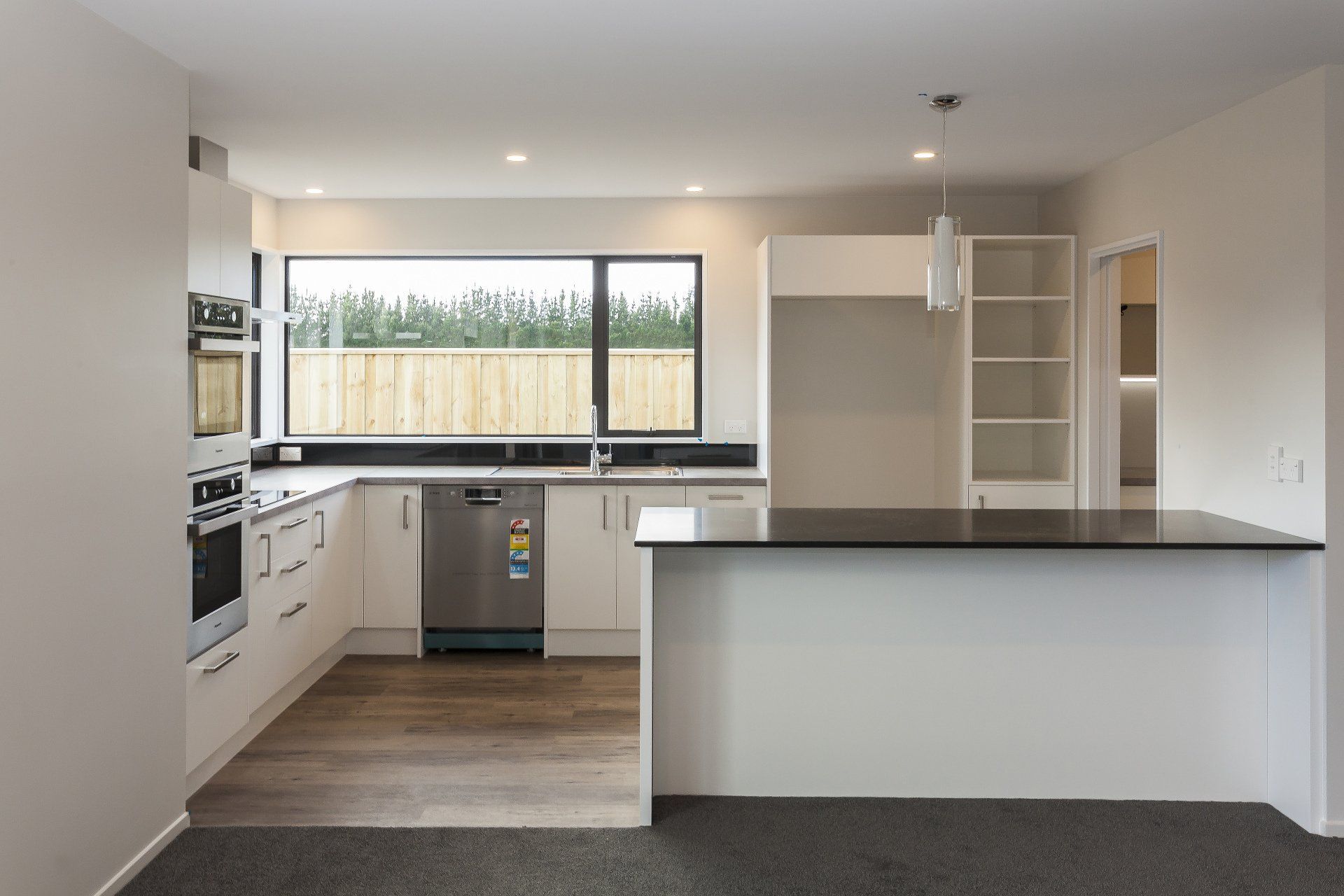 An empty kitchen with white cabinets and a black counter top
