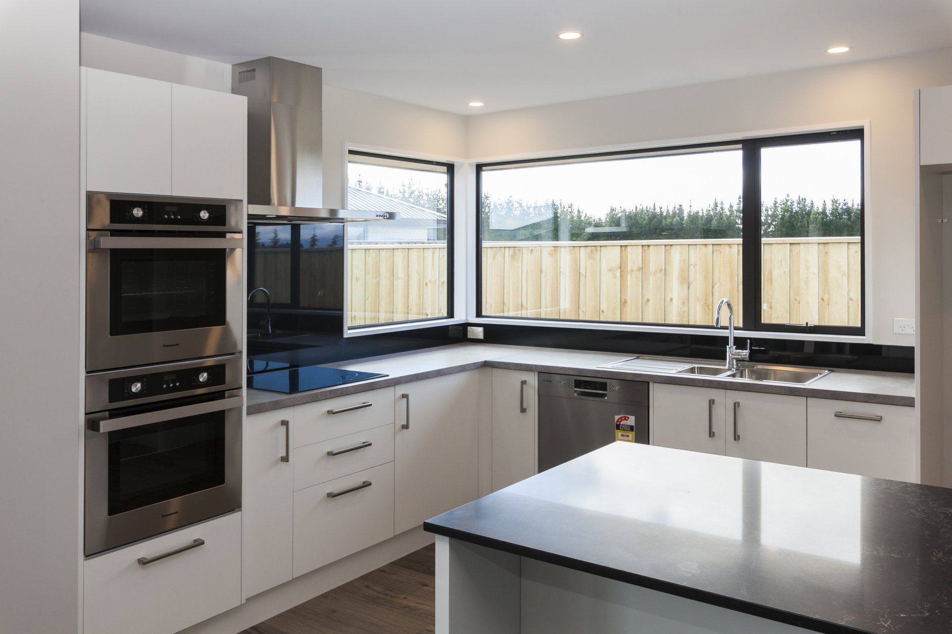 A kitchen with white cabinets , stainless steel appliances and a large island.