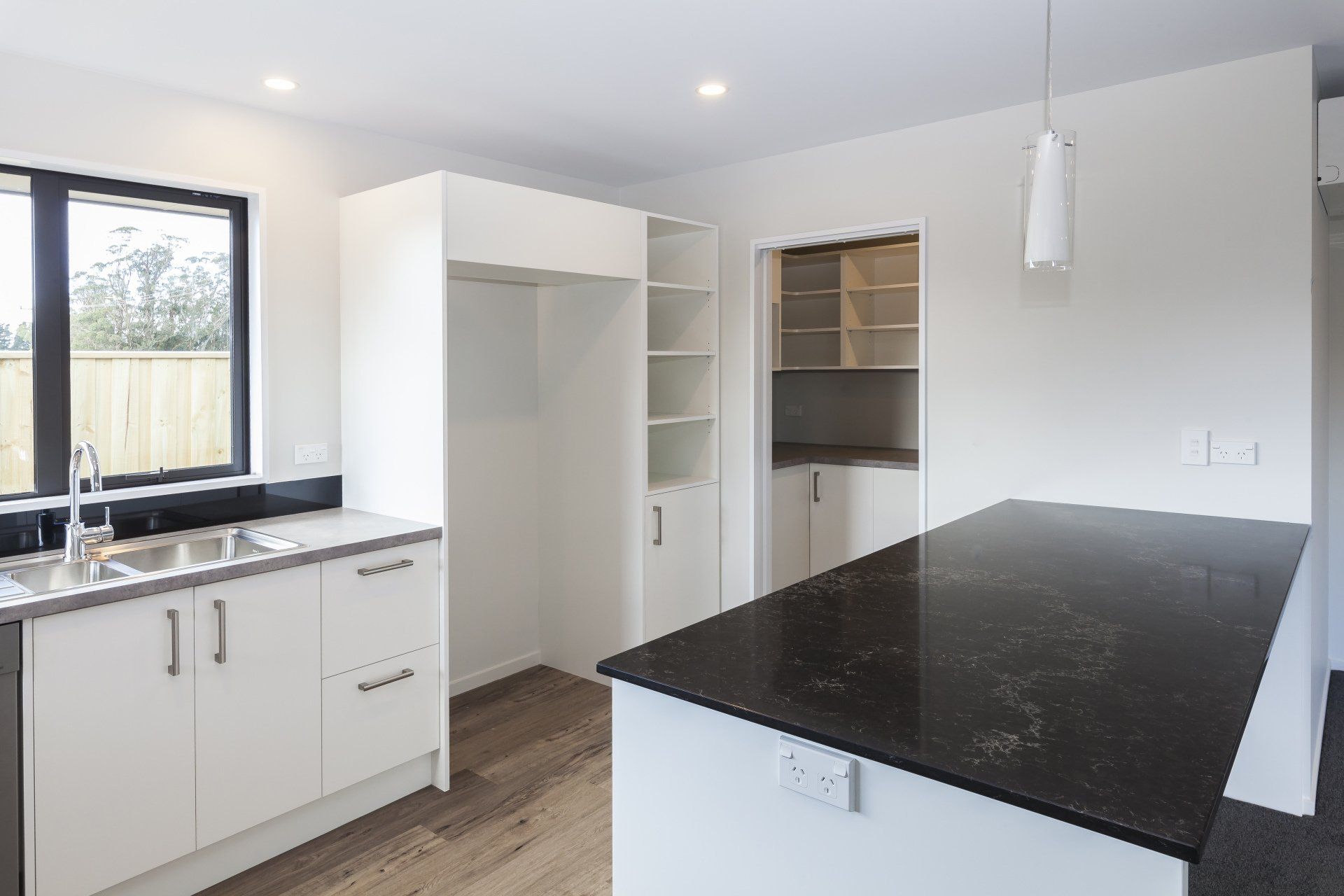 An empty kitchen with white cabinets and a black counter top.