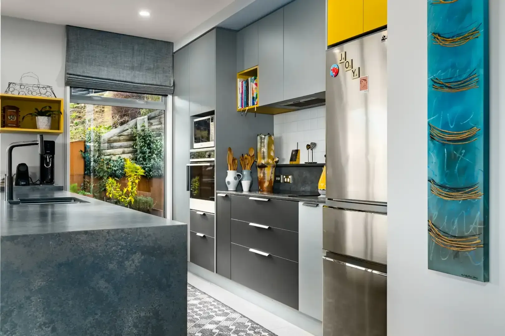 A kitchen with stainless steel appliances and a painting on the wall.