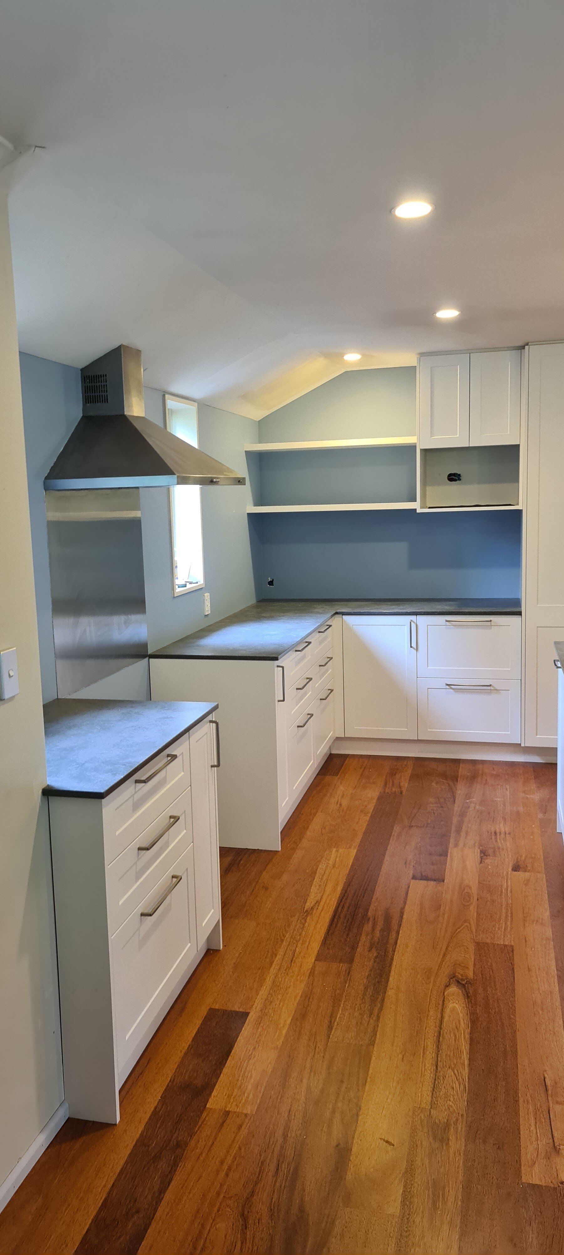 A kitchen with white cabinets and hardwood floors.