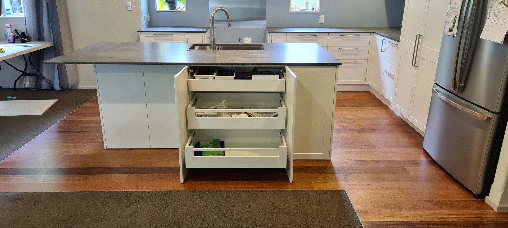 A kitchen with a large island with drawers open and a sink.