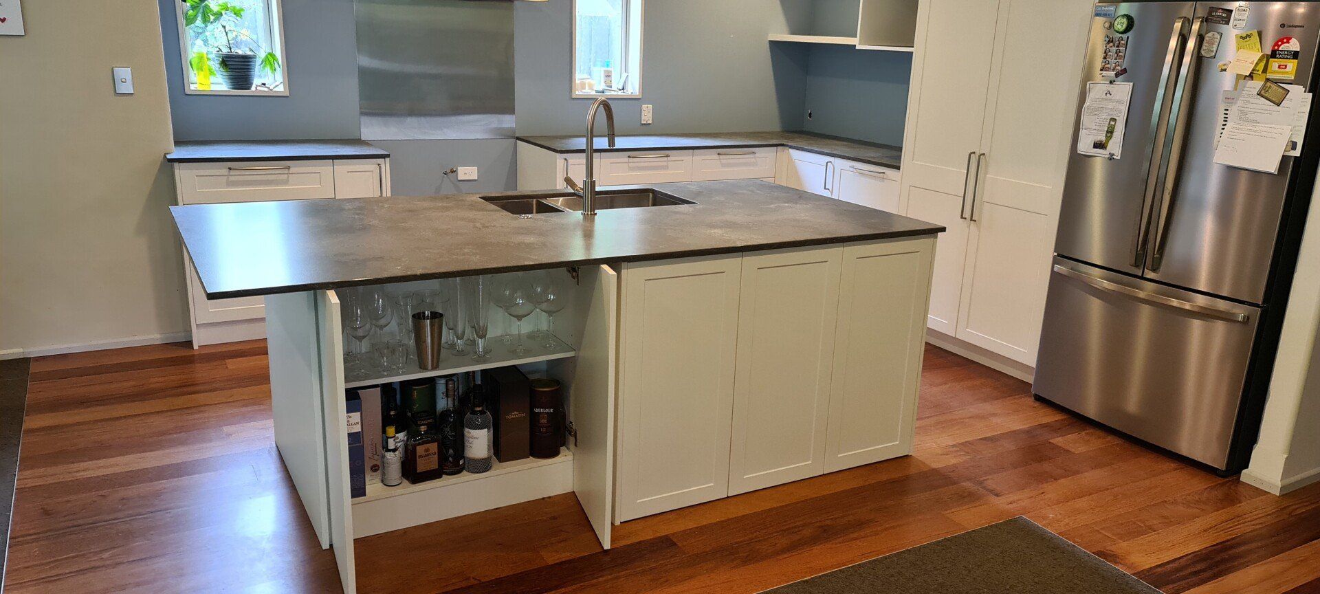 A kitchen with stainless steel appliances , a large island , a sink , and a refrigerator.
