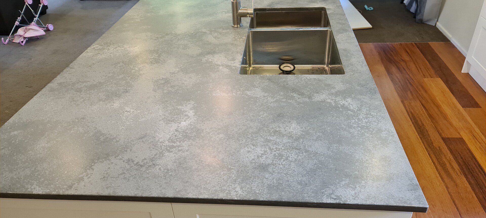 A kitchen counter with a sink and a wooden floor.