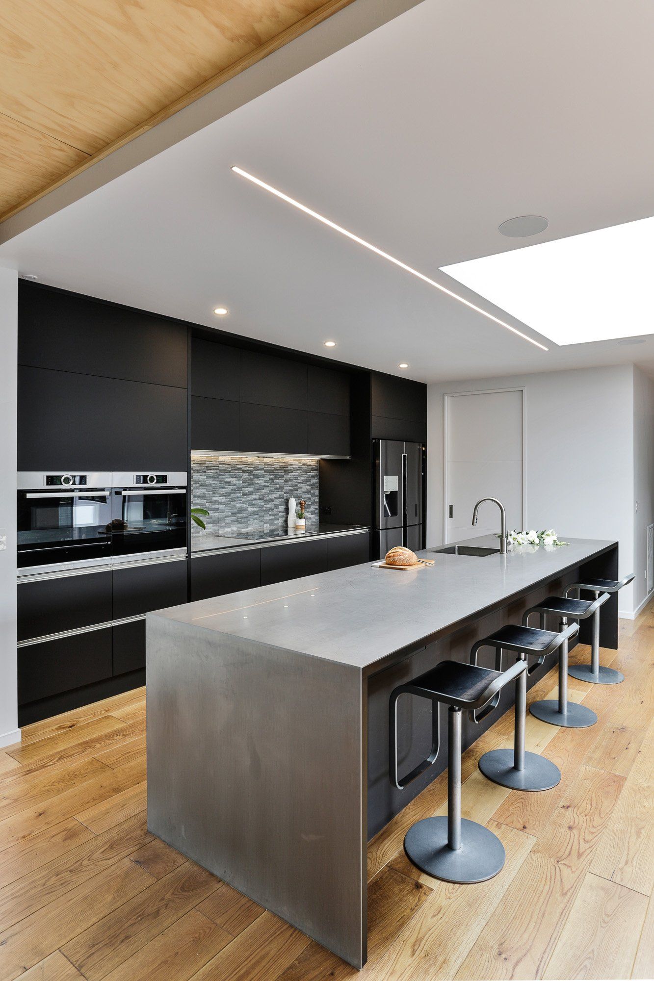 A kitchen with black cabinets and a large island with stools.