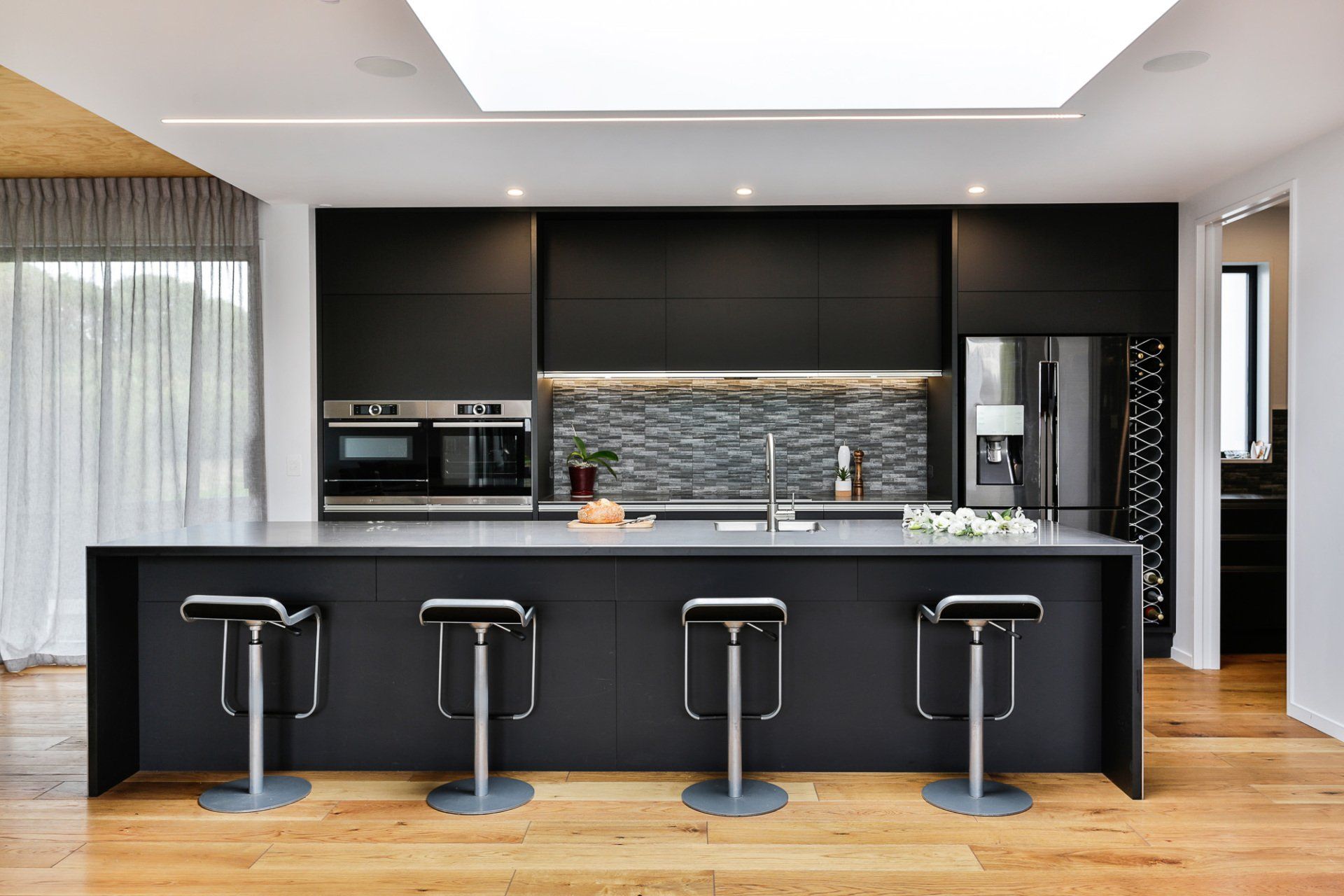 A kitchen with black cabinets and stools and a large island.