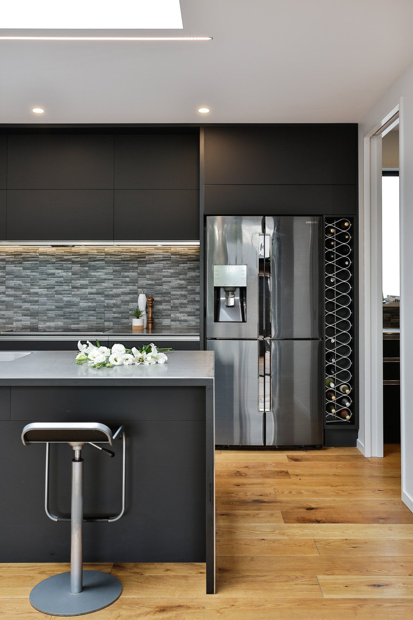 A kitchen with black cabinets and a stainless steel refrigerator.