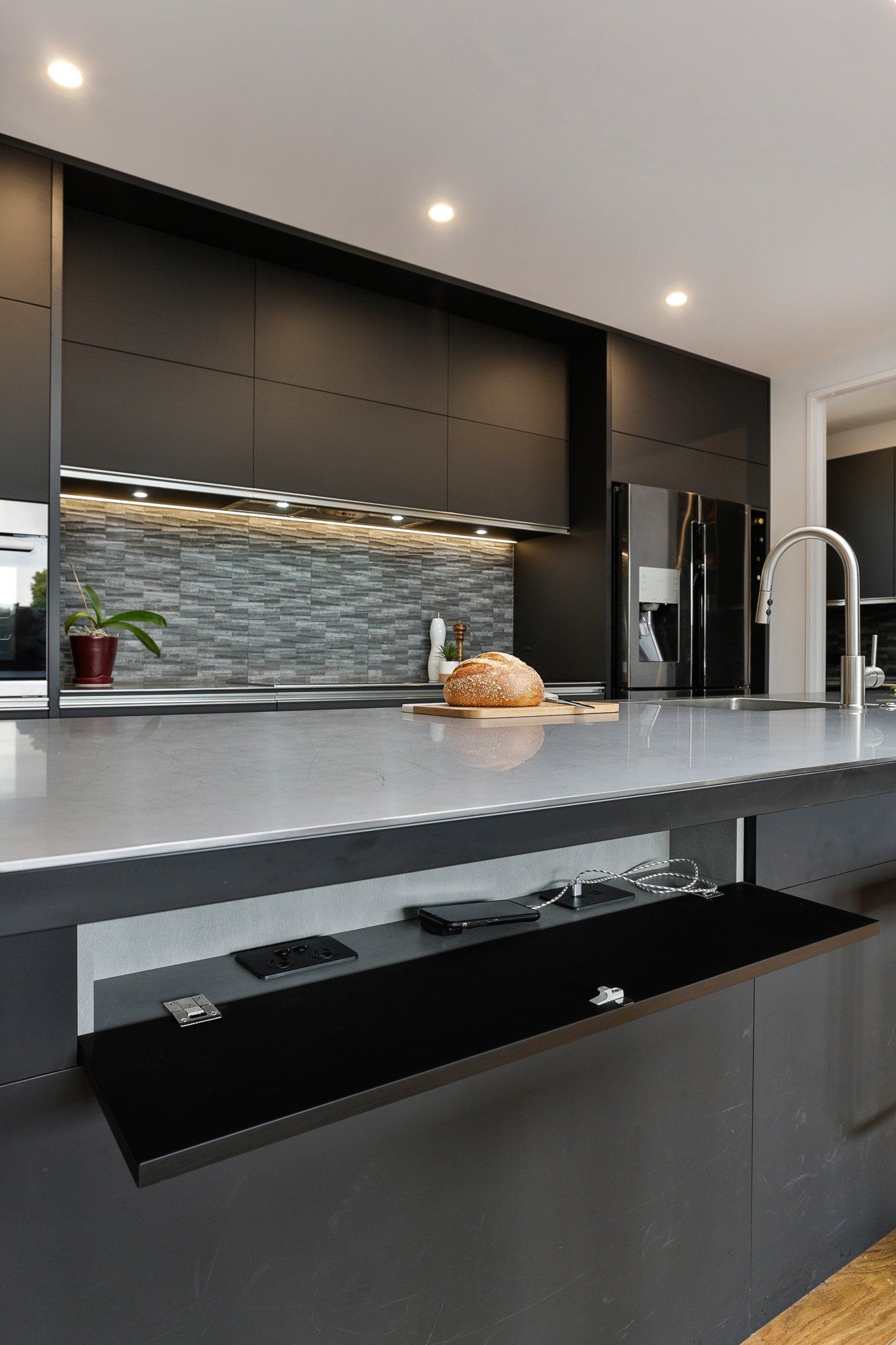 A kitchen with black cabinets and a bread loaf on the counter.