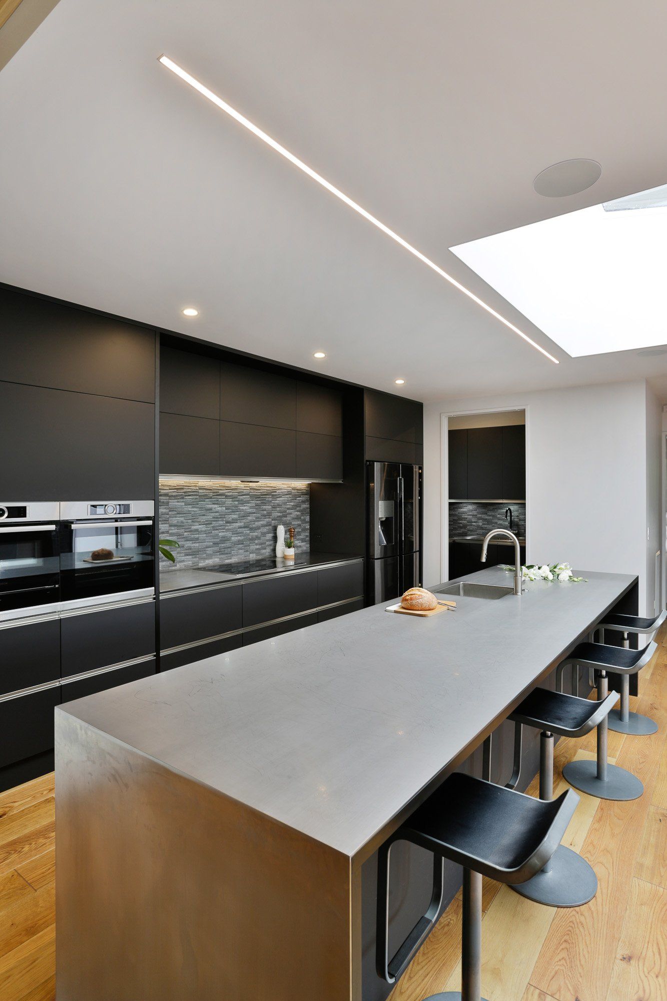 A kitchen with black cabinets and a large island with stools.