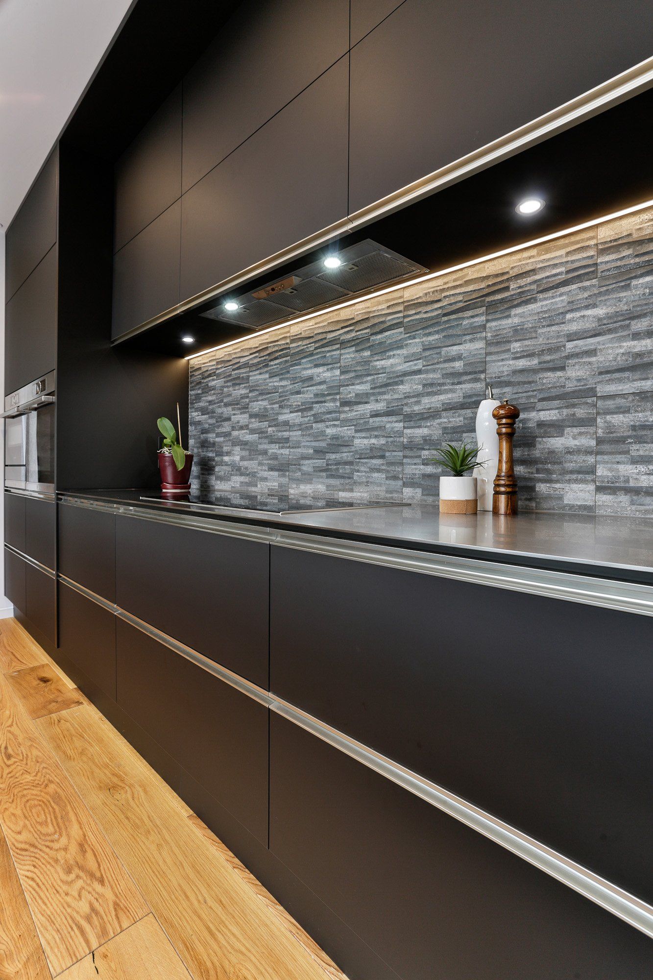 A kitchen with black cabinets and a stainless steel counter top.