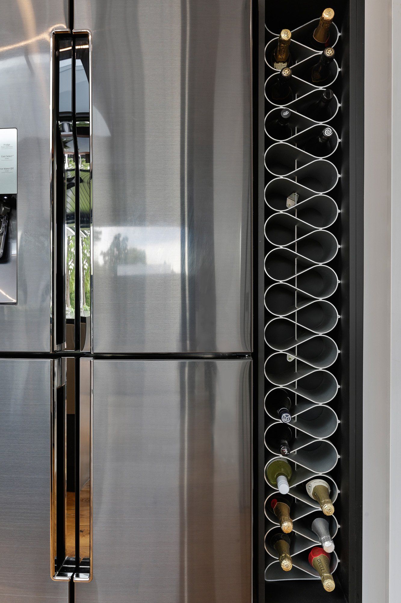 A stainless steel refrigerator with a wine rack attached to it.