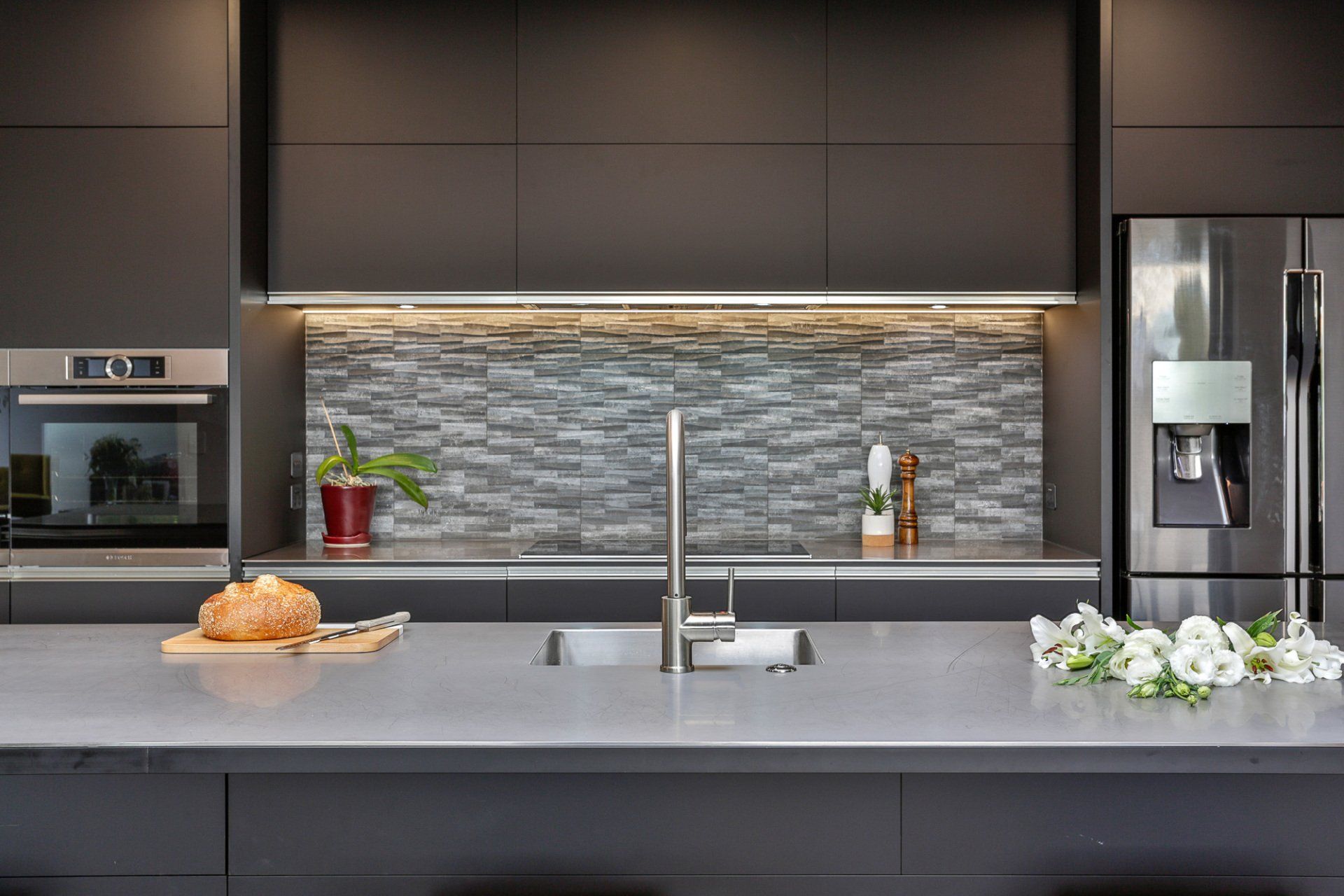 A kitchen with a sink , refrigerator , and oven.