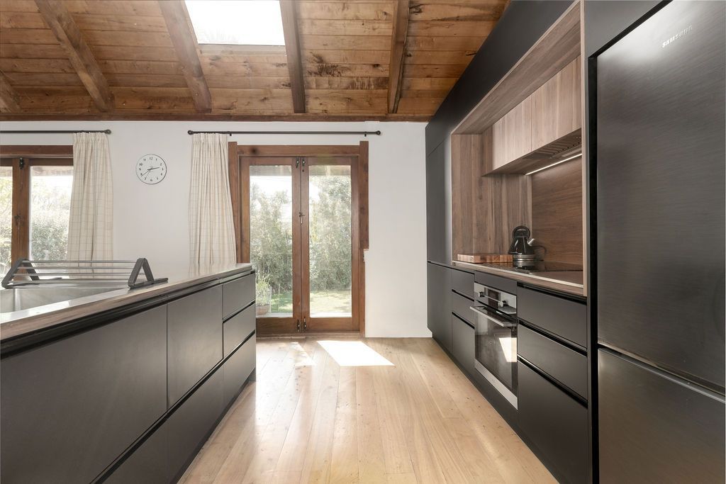 A kitchen with black cabinets and wooden floors and a wooden ceiling.