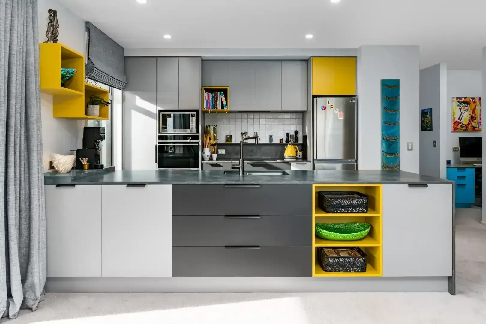 A kitchen with gray , white and yellow cabinets and a large island.