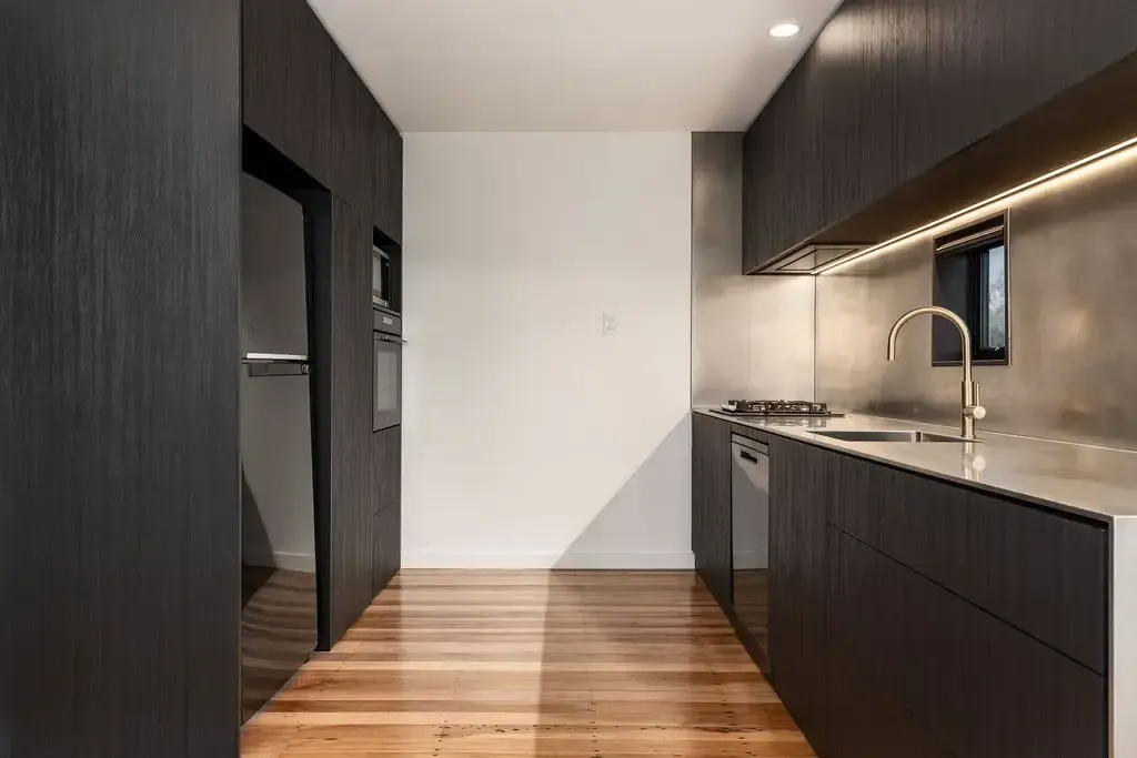 Dark wood kitchen with cabinetry and light wood floors.