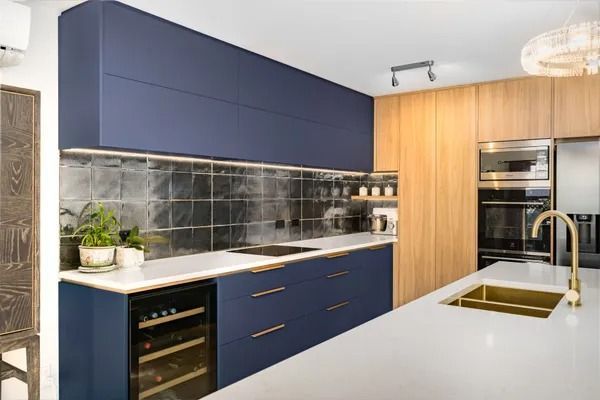 A kitchen with blue cabinets and a gold sink.