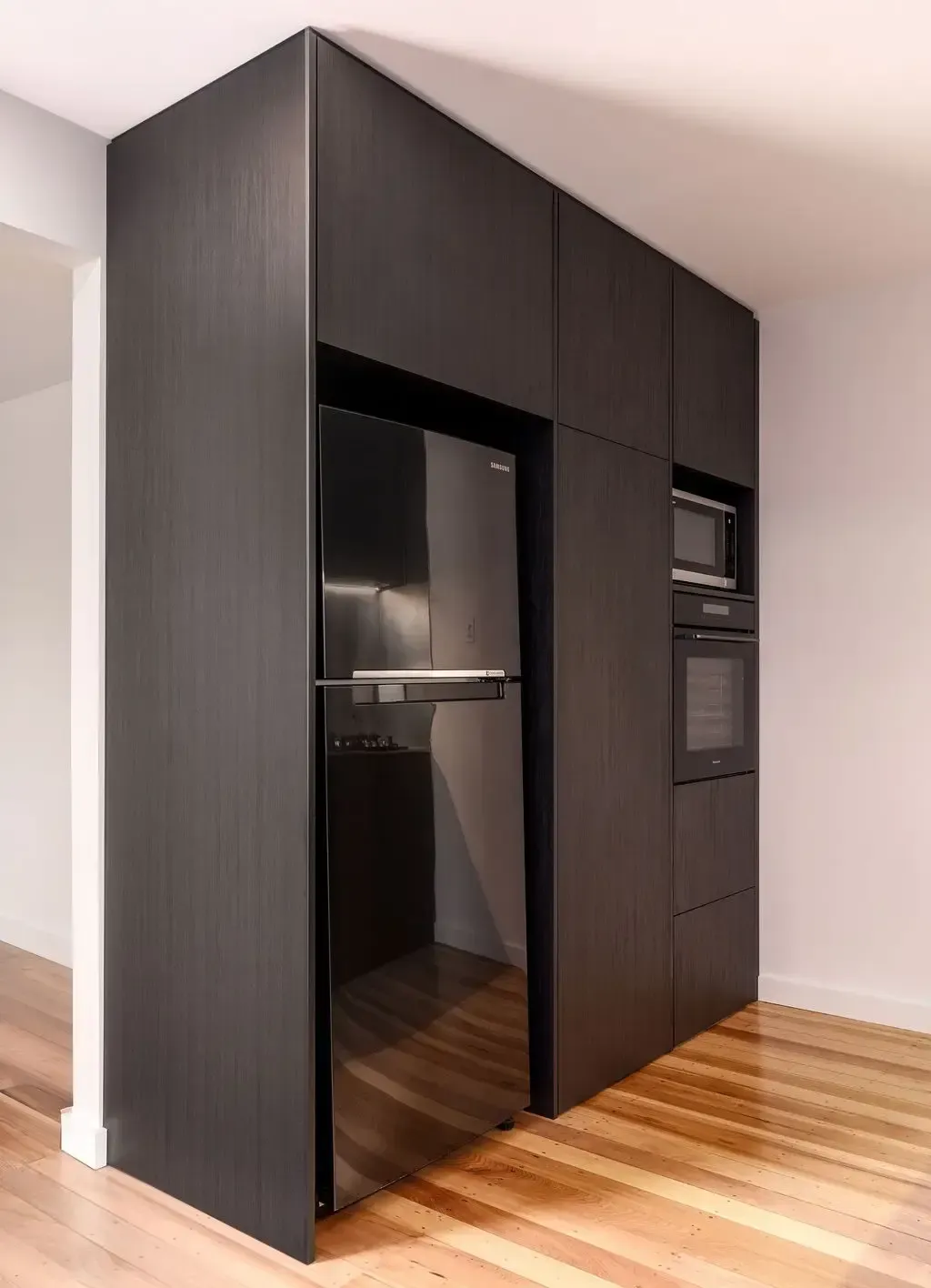 Dark wood kitchen cabinetry with a black refrigerator, microwave, and oven.