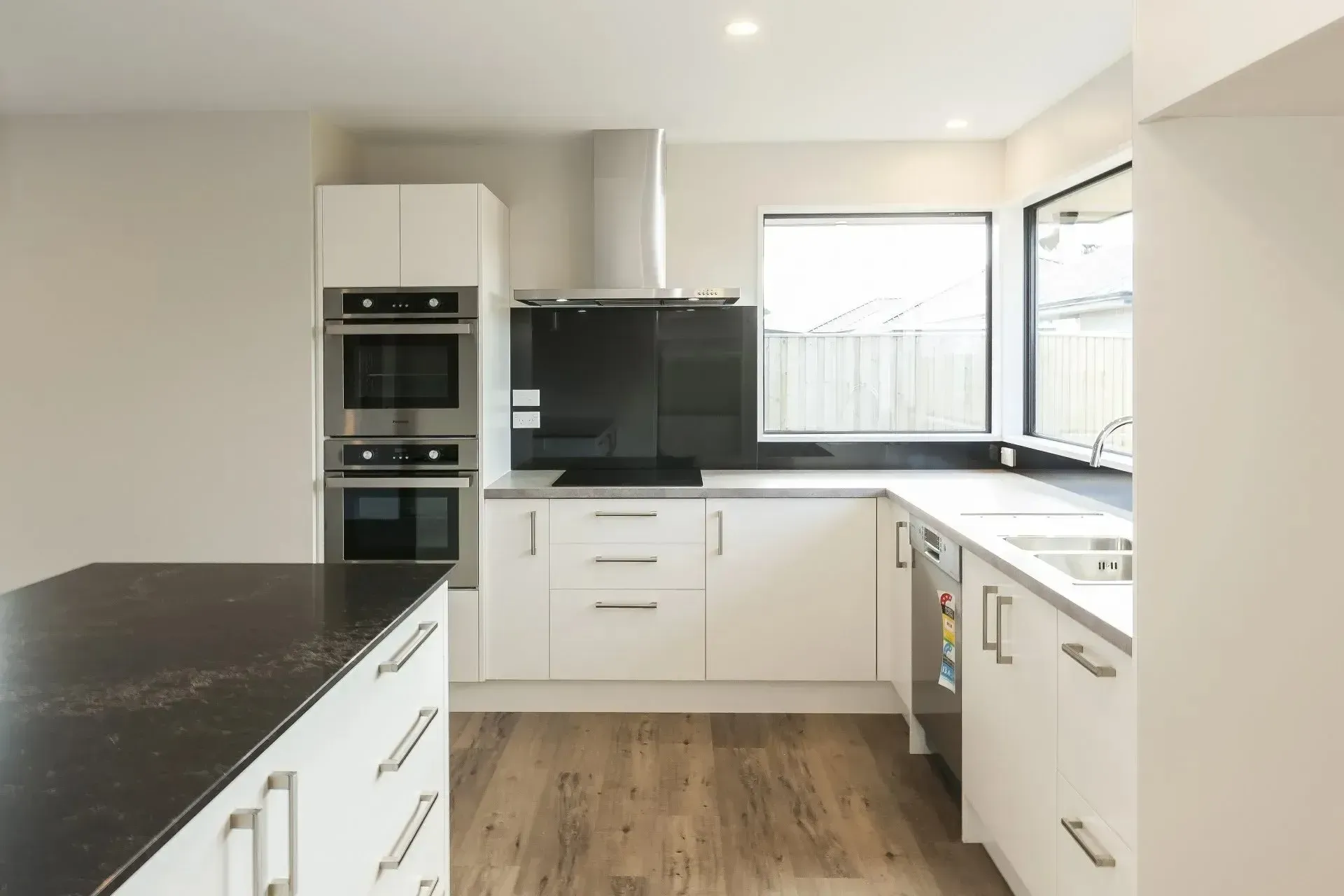 A kitchen with white cabinets , black counter tops and stainless steel appliances.