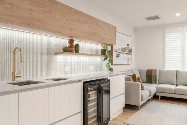 A living room with a couch , sink , and refrigerator.