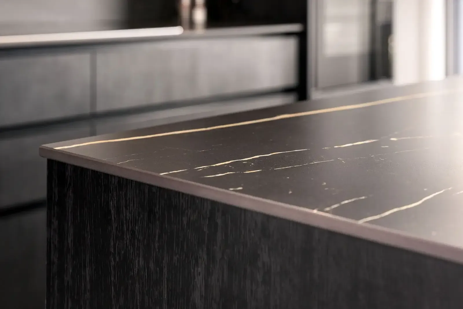 Dark kitchen island with marble-like countertop and subtle gold trim.